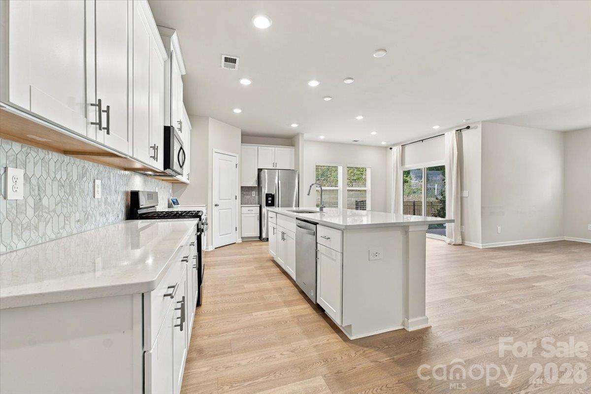 LVP flooring through all common areas, white kitchen (looks fantastic!), neutral paint, direct access to covered porch from large open floor plan - 151 Bird Dog Drive, Mooresville