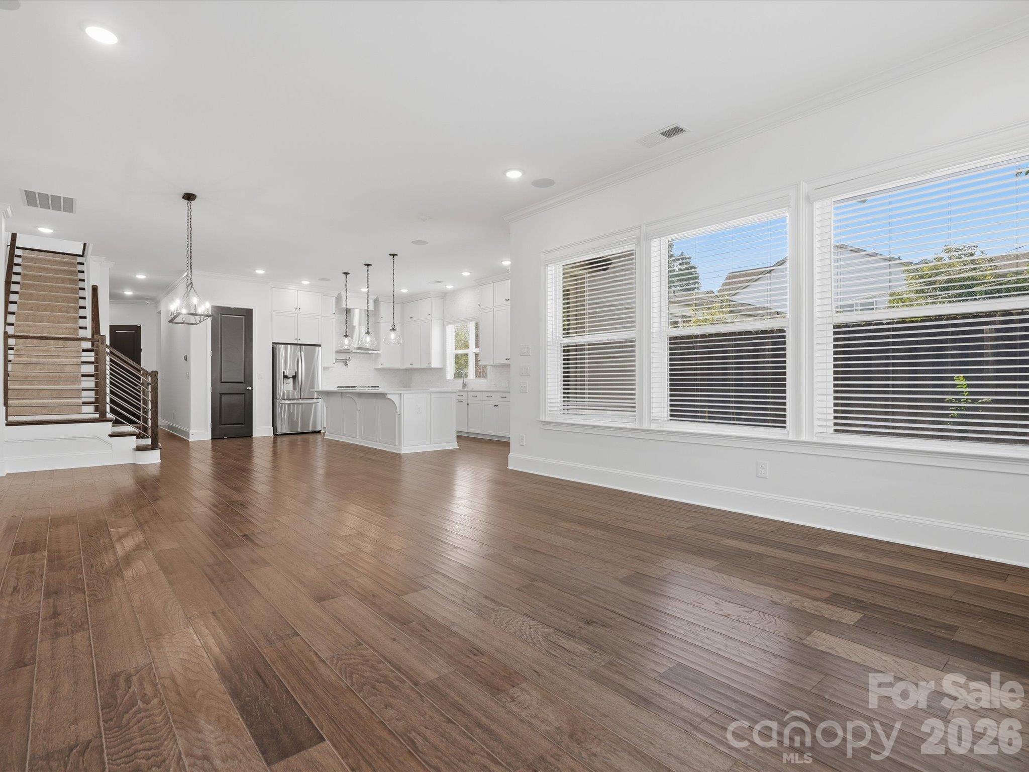 Open-concept great room with ten-foot ceilings, LVP flooring, oversized windows, and sightlines to the designer kitchen and modern staircase. Move-in-ready townhome near South End Charlotte. - 337 Belton Street, Charlotte