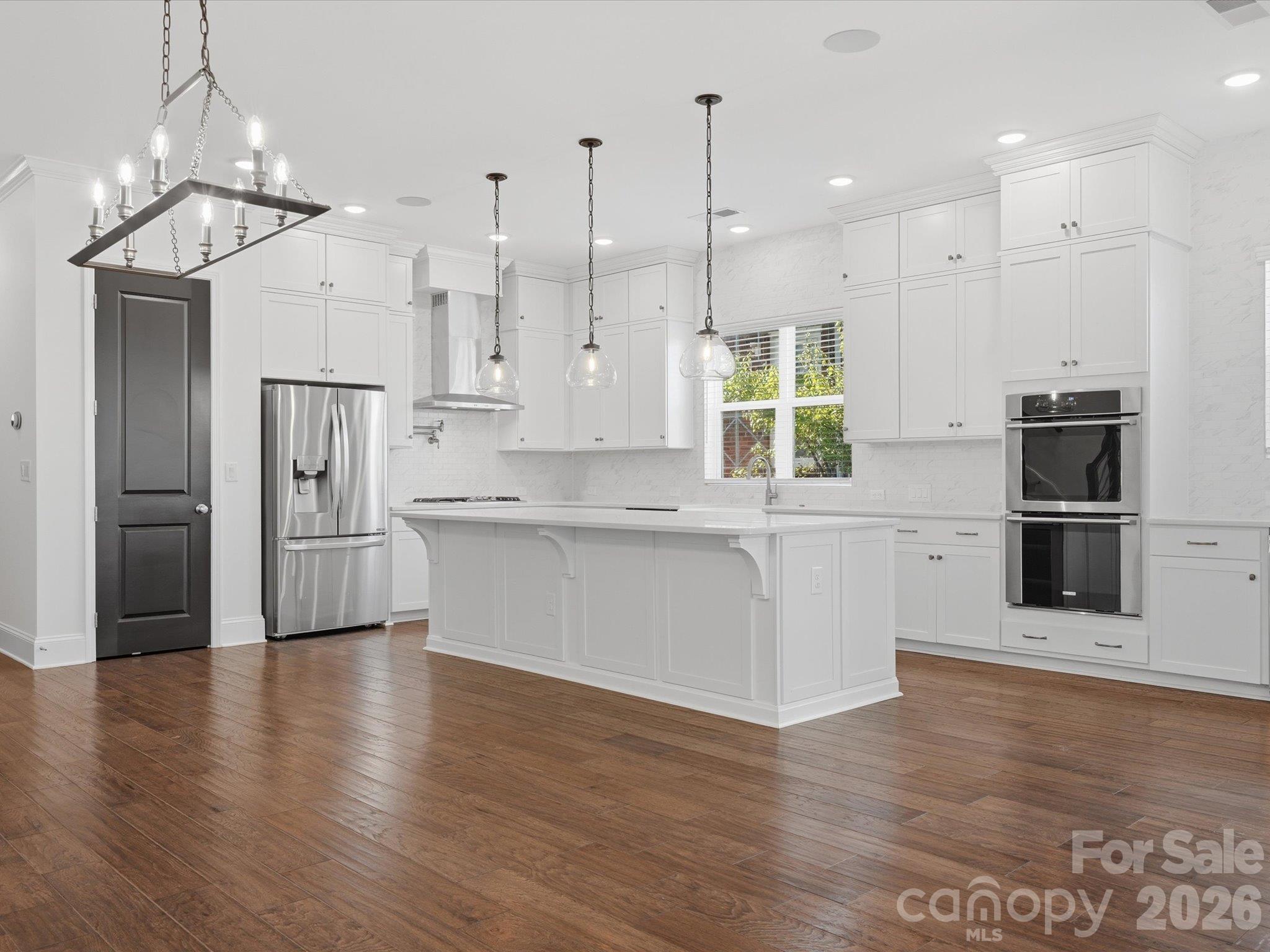 Kitchen and dining area with statement chandelier, oversized island, stainless steel appliances, and recessed lighting on a bright, open main level. - 337 Belton Street, Charlotte