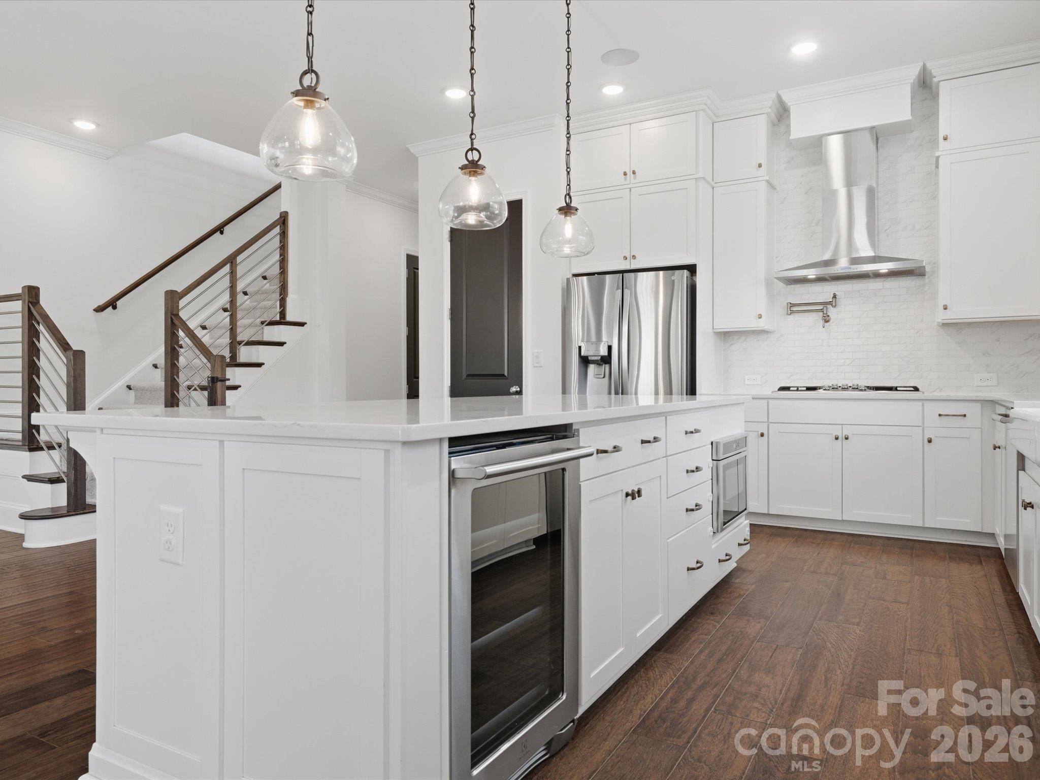 Oversized kitchen island with built-in wine refrigerator, microwave drawer, and seating overhang, overlooking the modern staircase and great room. - 337 Belton Street, Charlotte