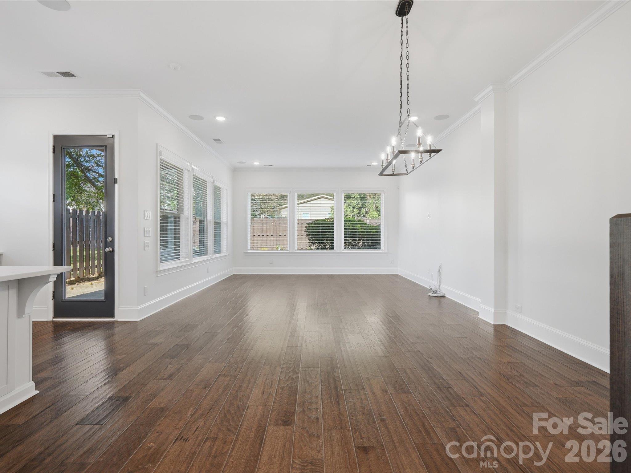 Spacious living room with a wall of windows overlooking the private fenced backyard, glass door to the covered patio, and ten-foot ceilings. - 337 Belton Street, Charlotte