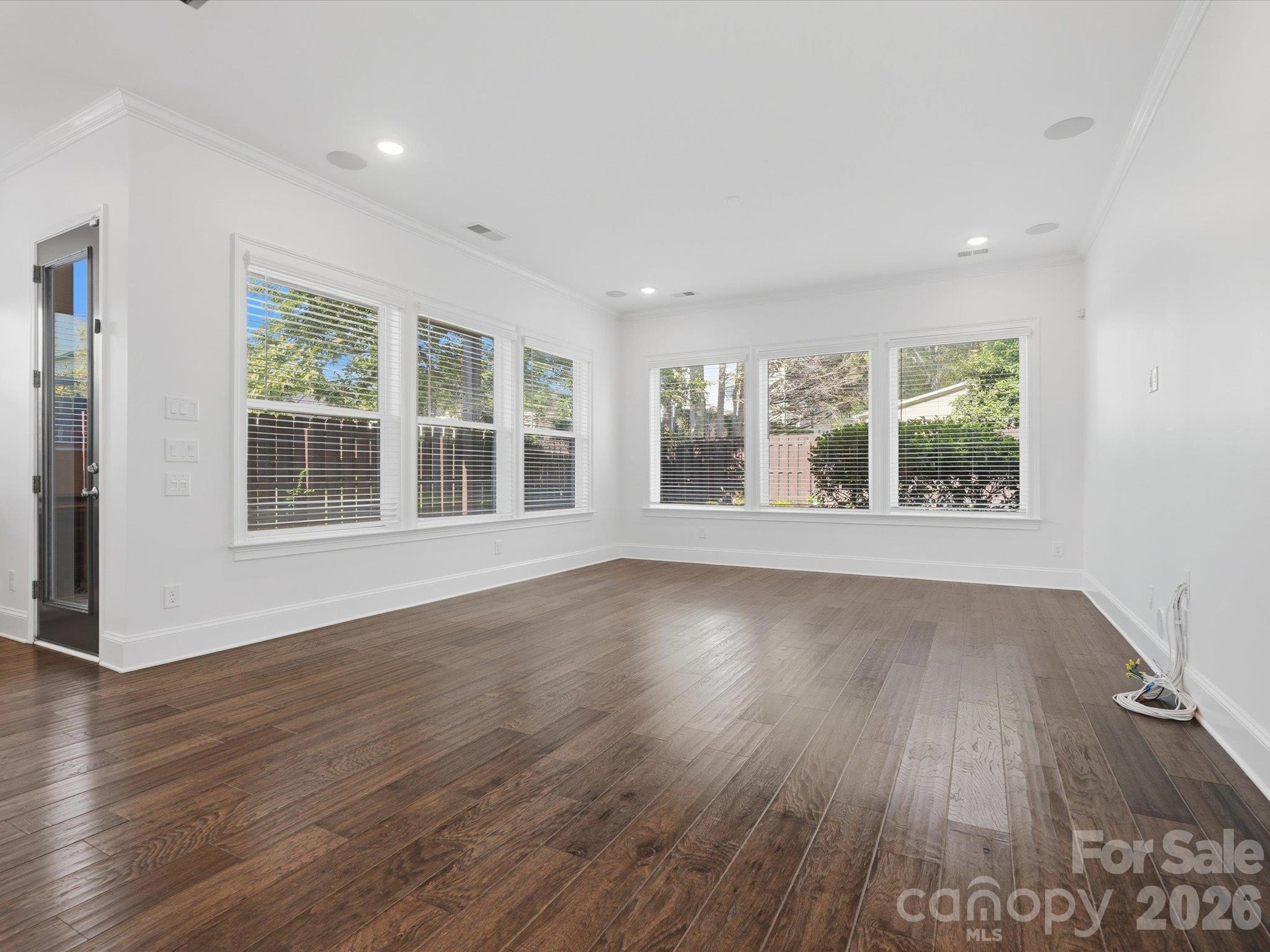 Living room with oversized windows on two walls, recessed lighting, ceiling speakers, and abundant natural light, a benefit of end-unit townhome living in Charlotte. - 337 Belton Street, Charlotte