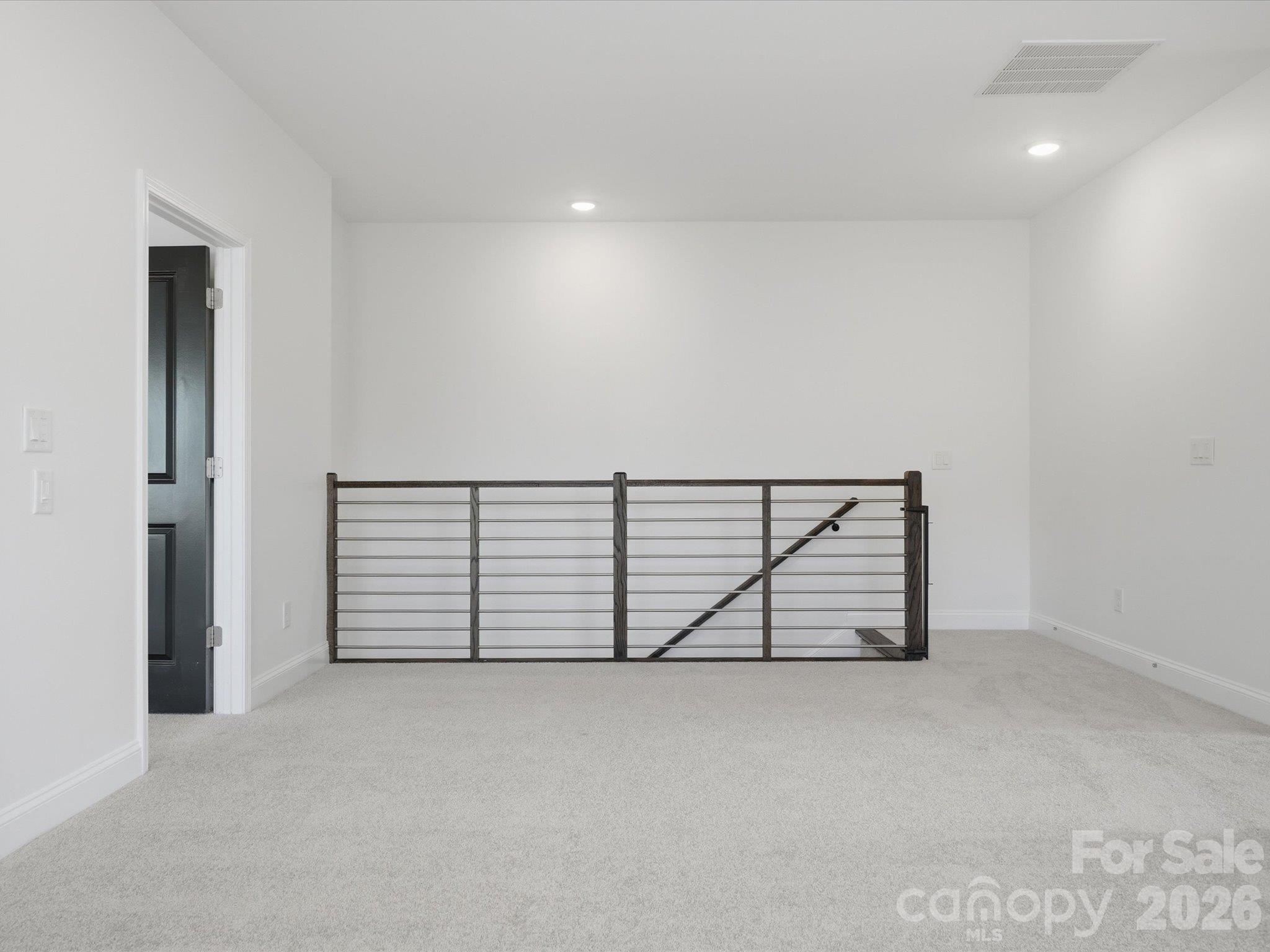 Upstairs landing with modern metal railing overlooking the staircase, connecting the bonus room, primary suite, and guest bedrooms. - 337 Belton Street, Charlotte
