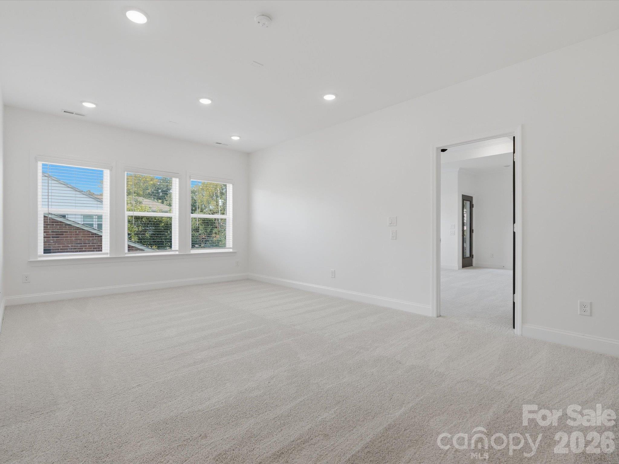 Second view of the upstairs bonus room showing its generous size, triple windows, plush carpet, and access to the second-floor hallway. - 337 Belton Street, Charlotte