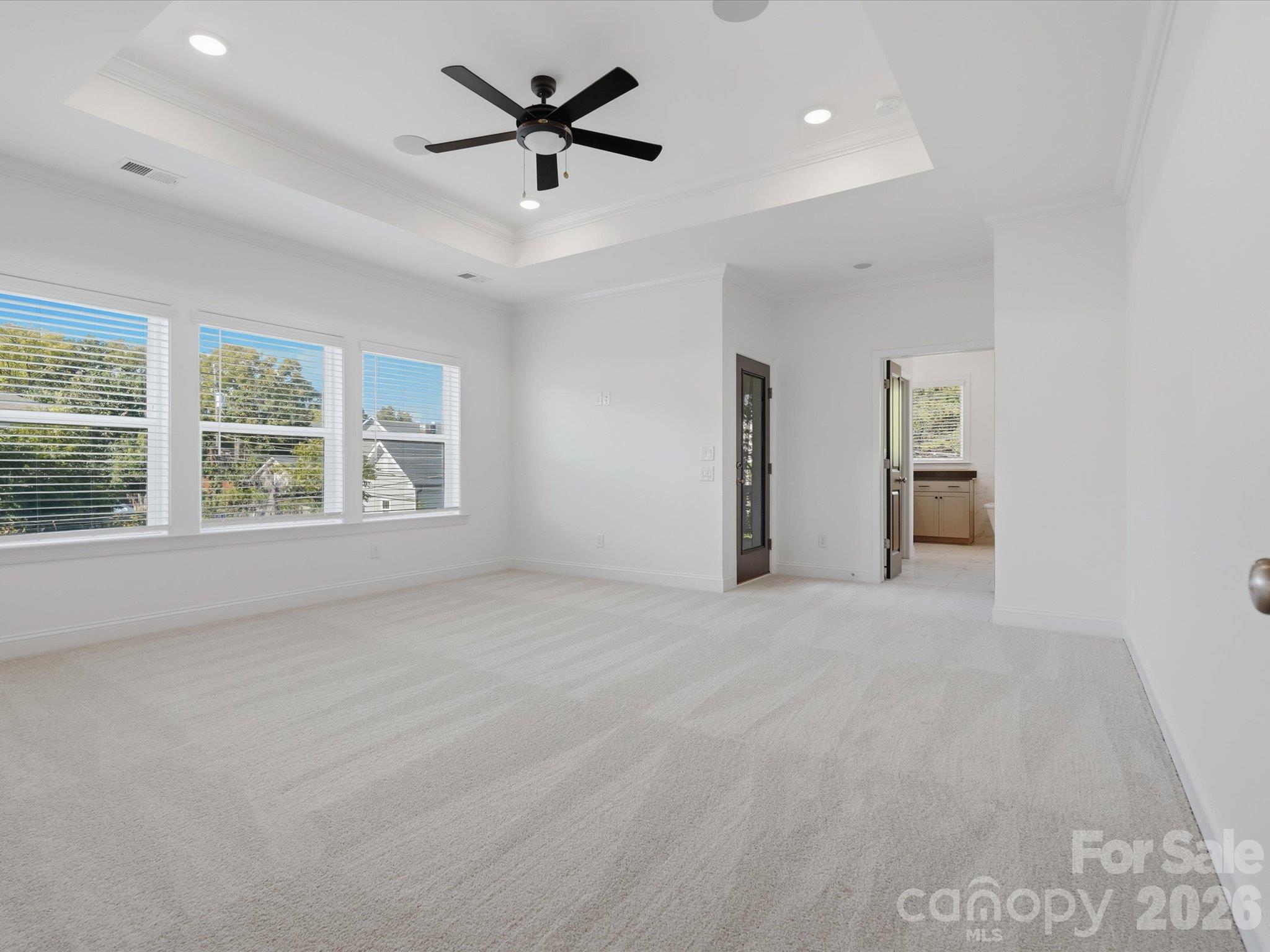 Primary bedroom suite with tray ceiling, ceiling fan, triple windows, and door to the private rear upper deck. Opens to the spa-inspired primary bath. - 337 Belton Street, Charlotte