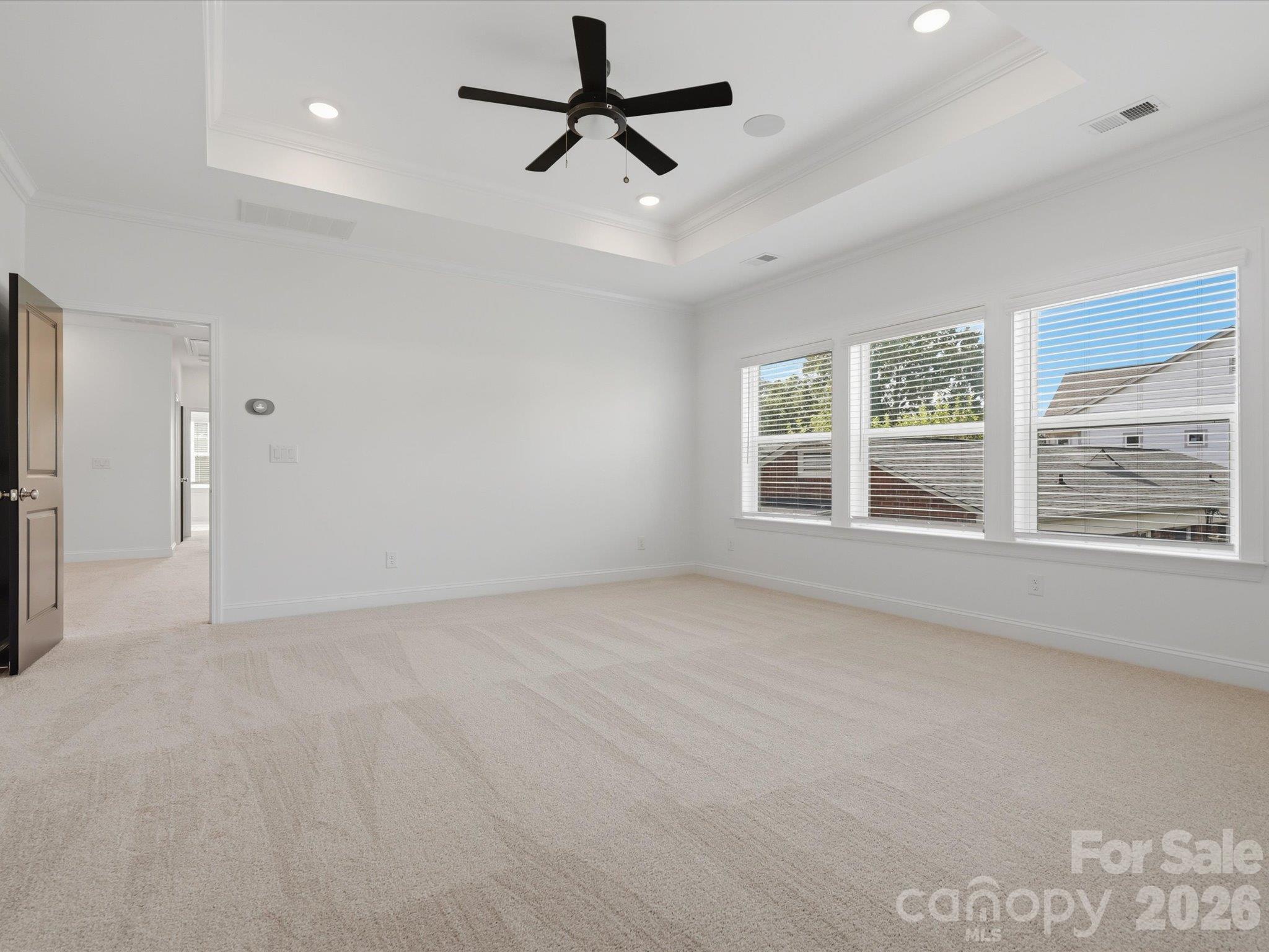 Primary suite with tray ceiling, ceiling fan, wall of windows, and plush carpet. Generous room for a king bed and sitting area. - 337 Belton Street, Charlotte