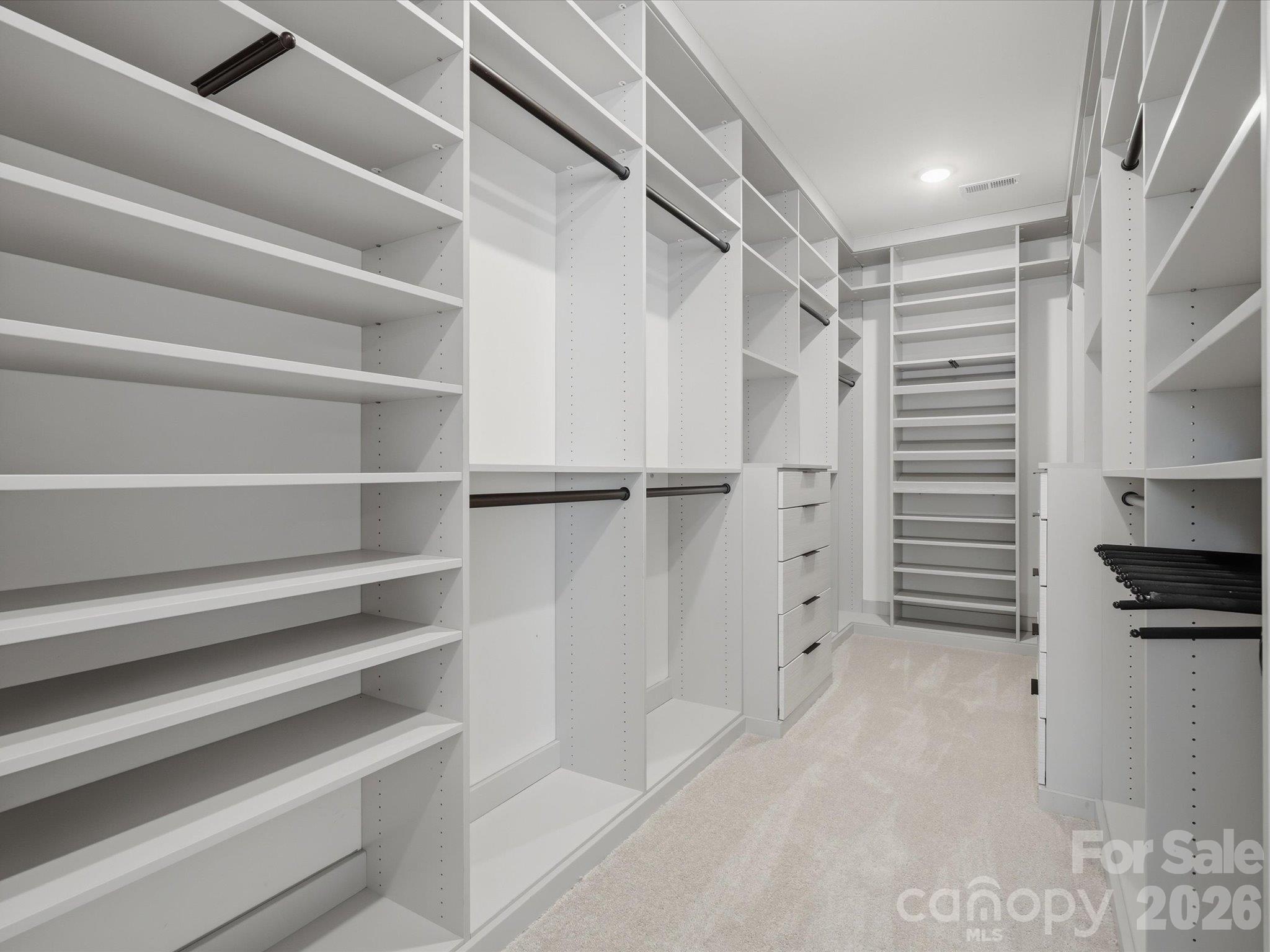 Custom primary walk-in closet with floor-to-ceiling built-in shelving, double hanging rods, drawers, and dedicated shoe storage. - 337 Belton Street, Charlotte