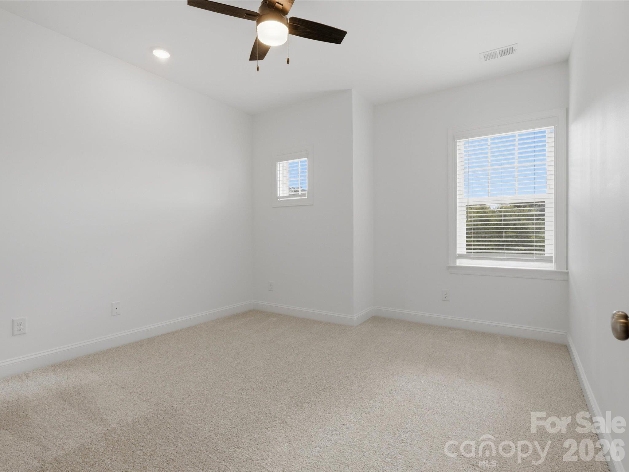 Upstairs third guest bedroom with ceiling fan, two windows, and plush carpet, near the full guest bathroom. - 337 Belton Street, Charlotte