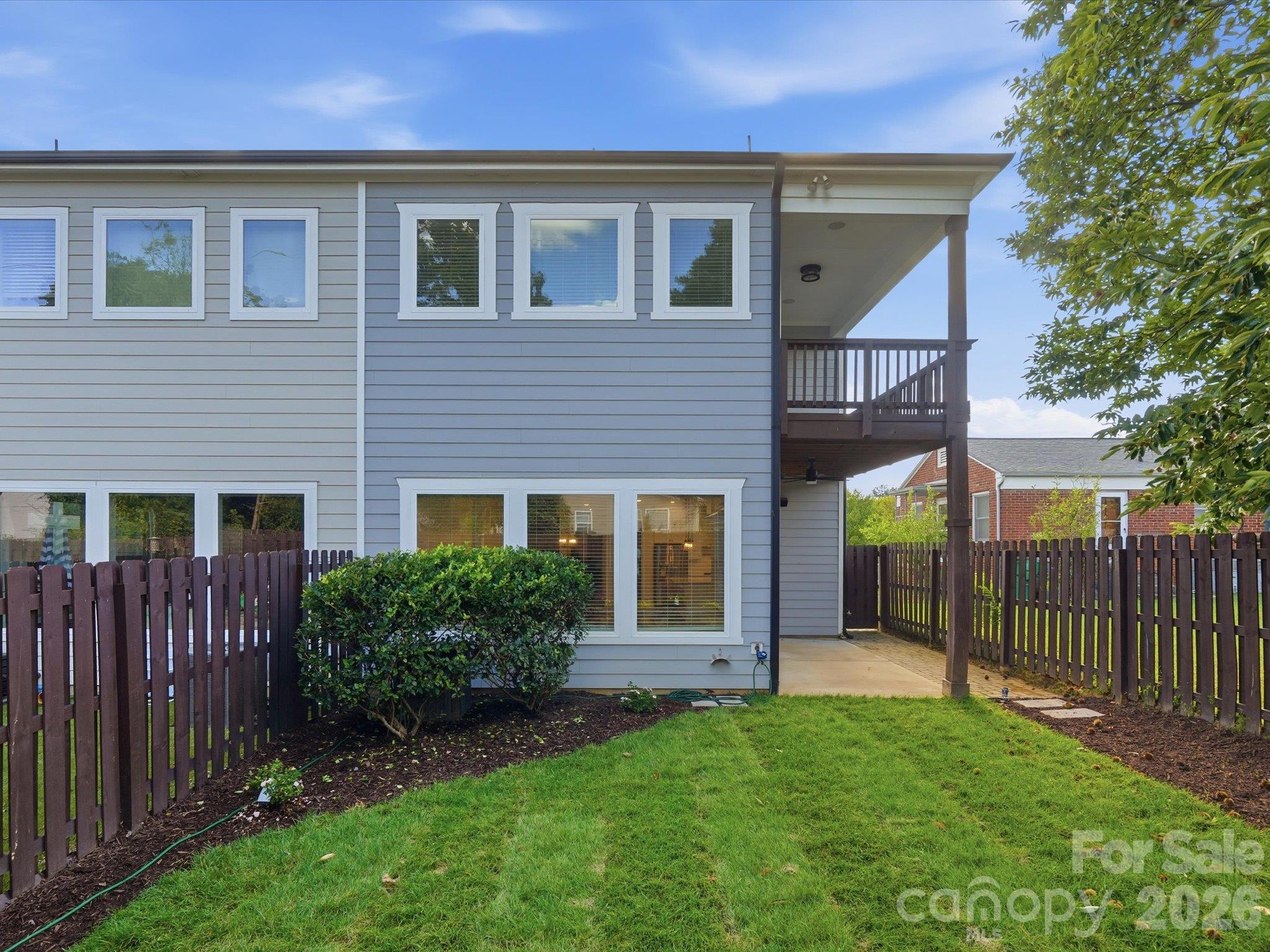 Back of home with abundant windows, covered patio, upper deck, and a level, fully fenced lawn offering private outdoor space near South End. - 337 Belton Street, Charlotte