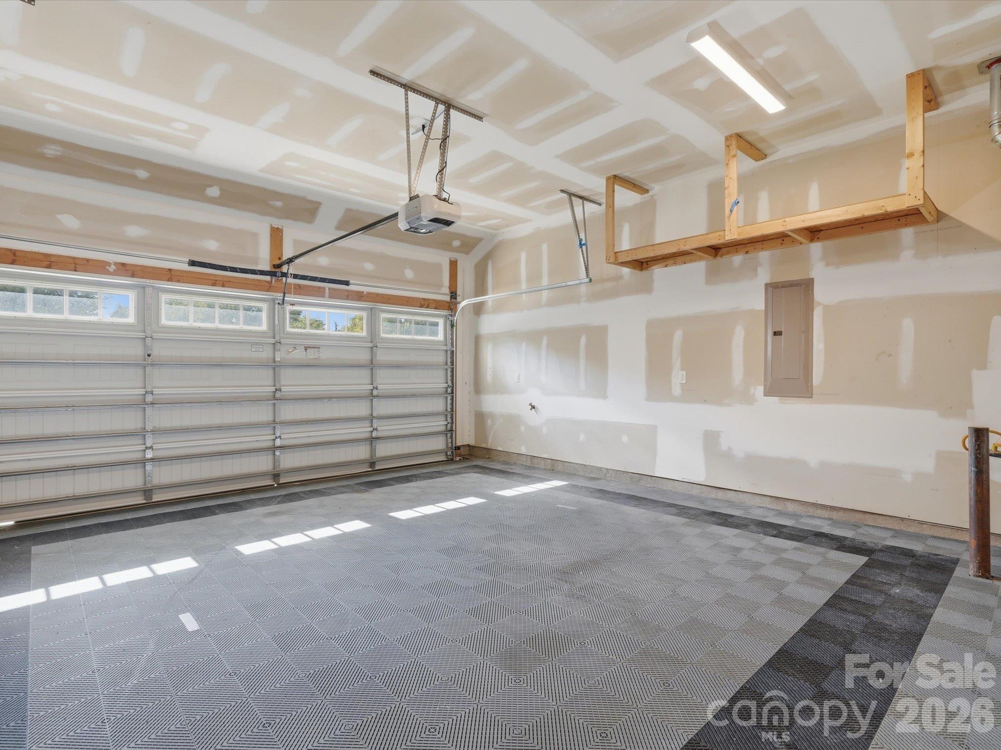 Attached two-car garage with interlocking tile flooring, overhead storage racks, LED lighting, and automatic garage door opener. - 337 Belton Street, Charlotte