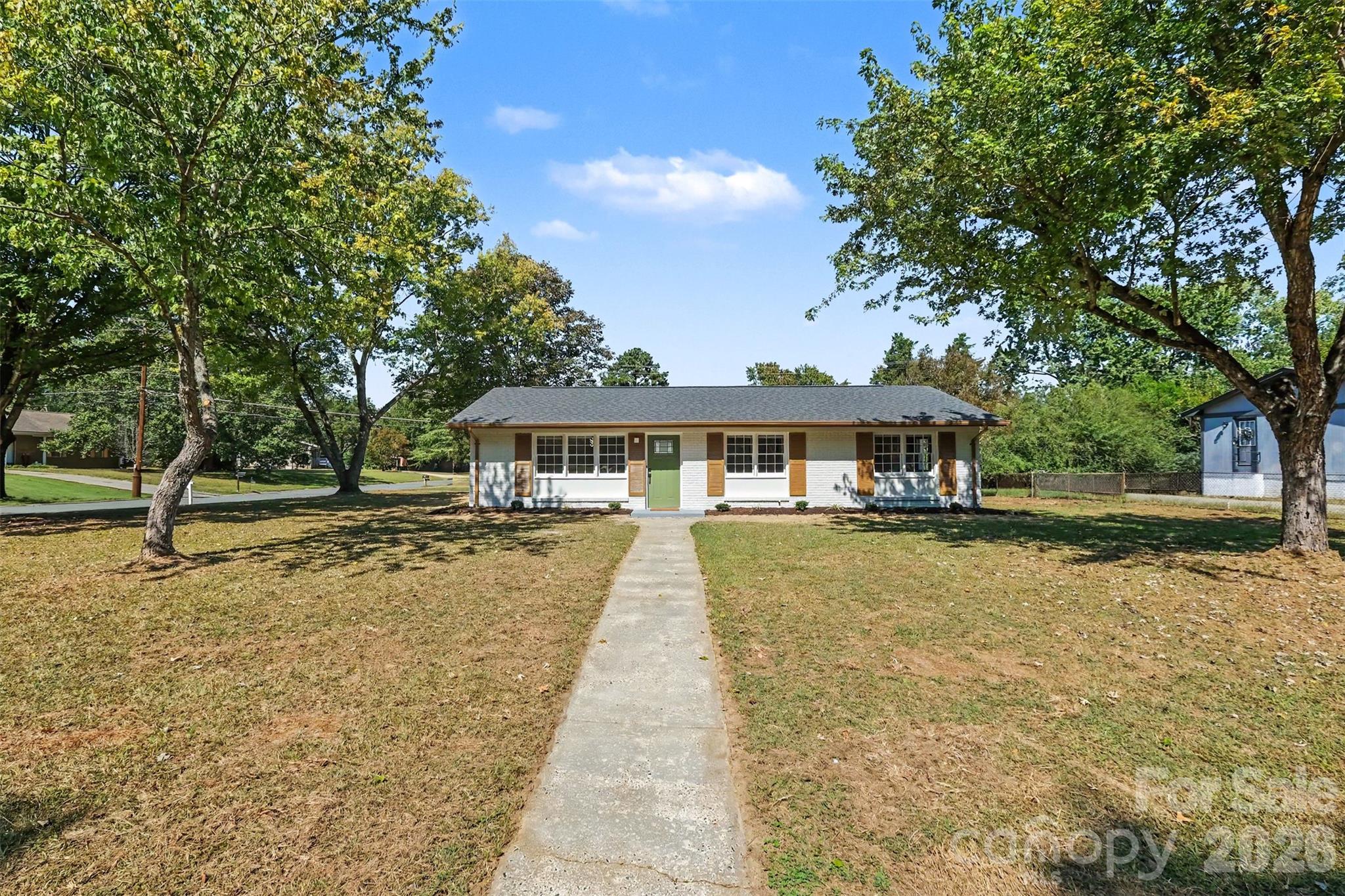 Spacious front yard setting highlighting the property's great curb appeal, mature shade trees, and newly renovated single-story home. - 3801 Hillock Court, Charlotte