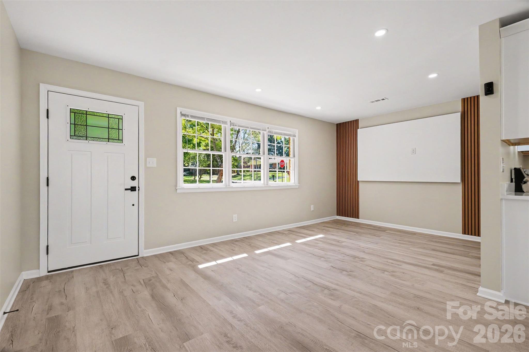 Bright living area highlighted by a stylish wood-accent feature wall, ideal for media and TV placement. - 3801 Hillock Court, Charlotte