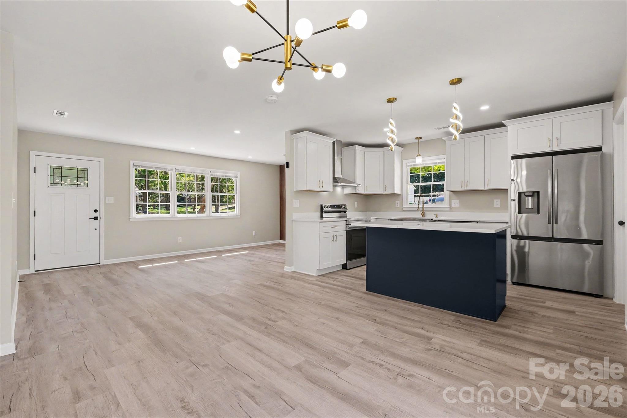 Seamless open-concept layout connecting the dining space, living room, and modern kitchen with a contrasting center island. - 3801 Hillock Court, Charlotte