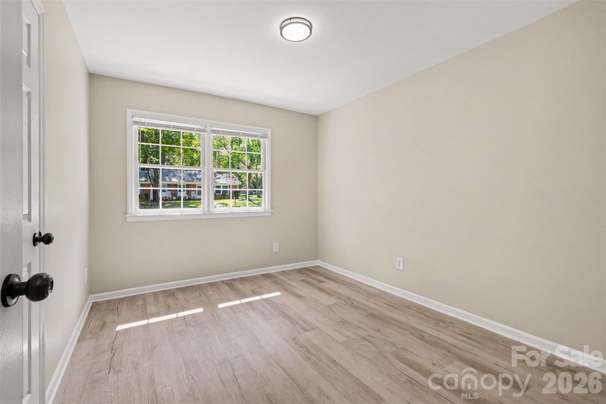 Secondary bedroom featuring fresh neutral paint, updated vinyl flooring, flush-mount lighting, and ample natural light. - 3801 Hillock Court, Charlotte