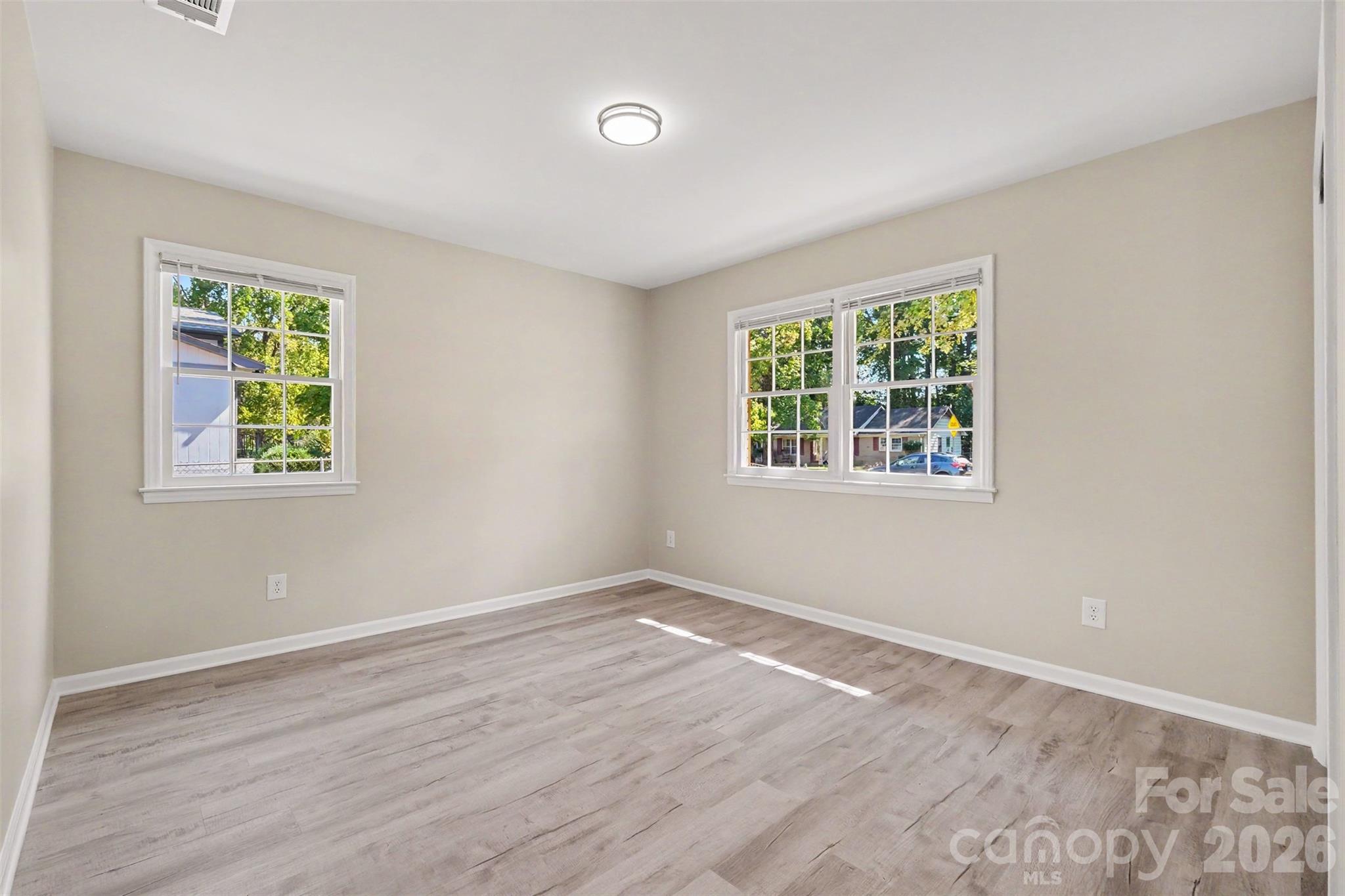 Spacious bedroom highlighted by double windows for ample natural light, fresh paint, and updated flooring. - 3801 Hillock Court, Charlotte