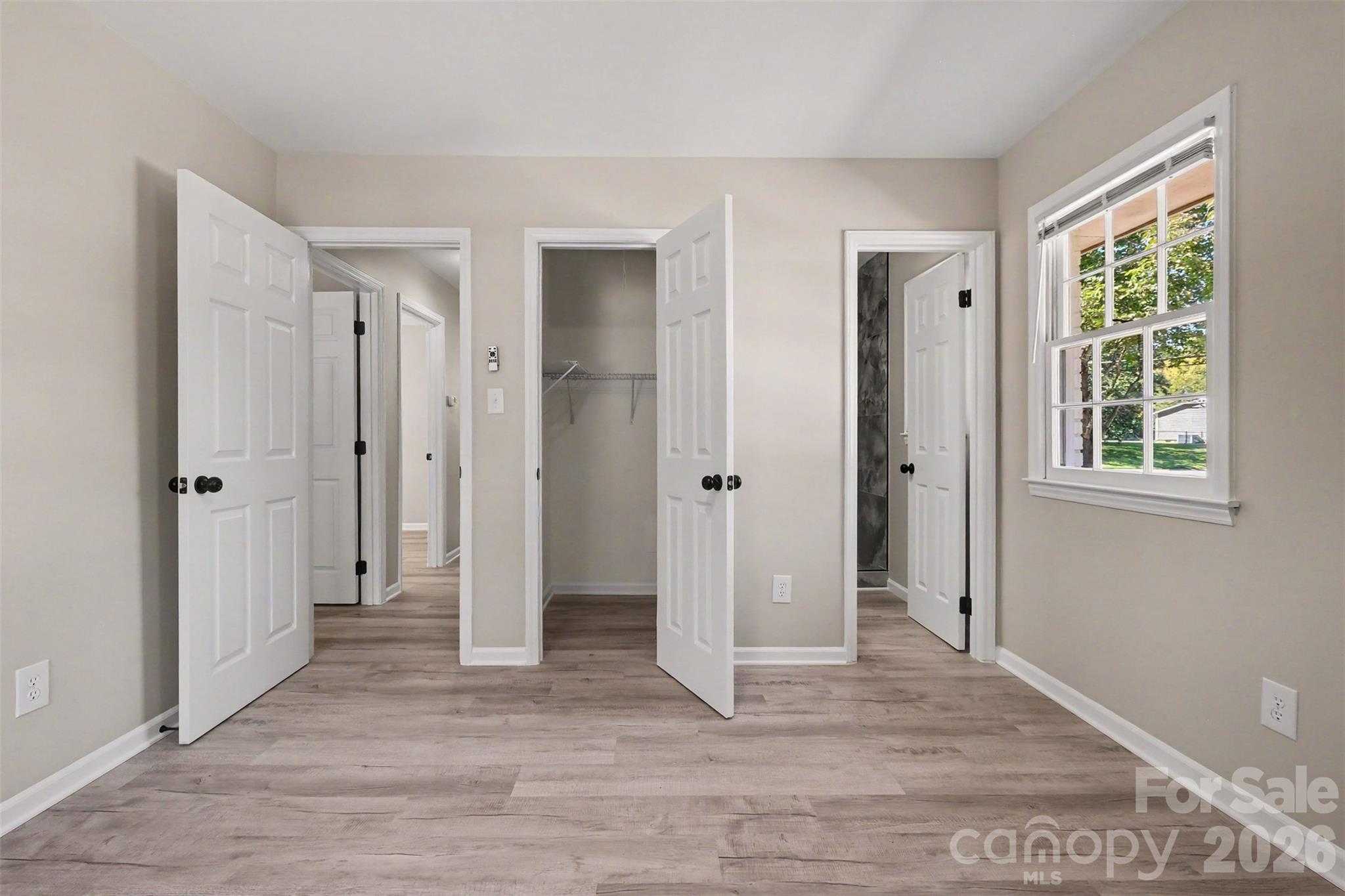 Primary bedroom featuring an open walk-in closet, fresh neutral paint, and direct access to the private ensuite bathroom. - 3801 Hillock Court, Charlotte
