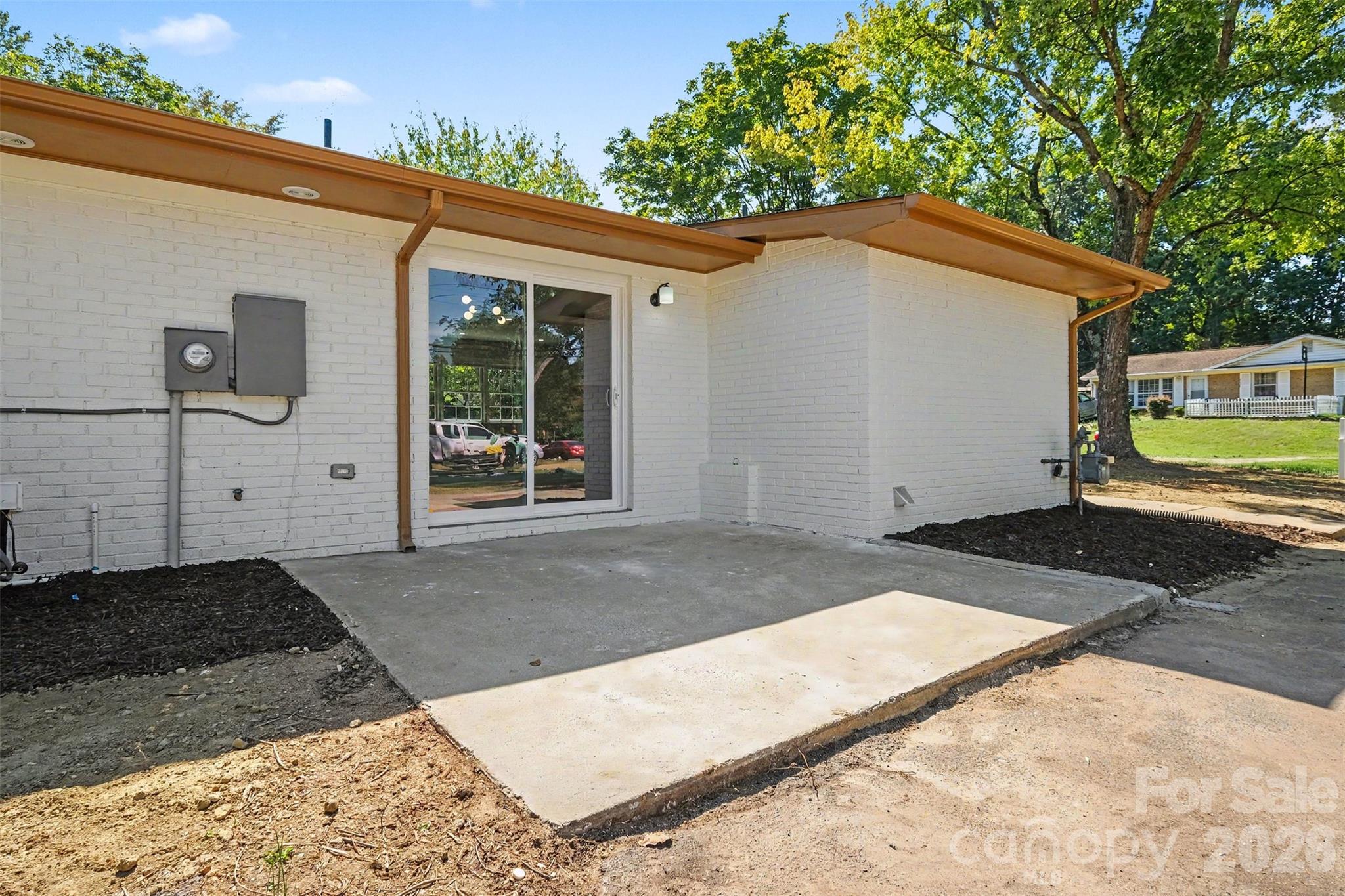 Outdoor patio space ideal for entertaining, showcasing new gutters, painted brick exterior, and direct sliding door access to the home. - 3801 Hillock Court, Charlotte