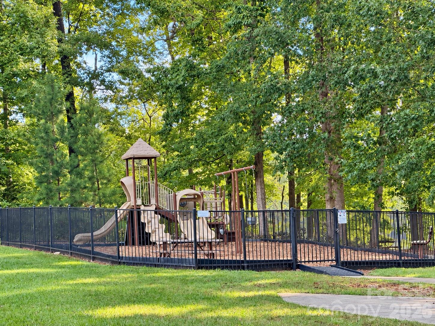 Community playground surrounded by lush trees. - 8149 Merryvale Lane, Charlotte