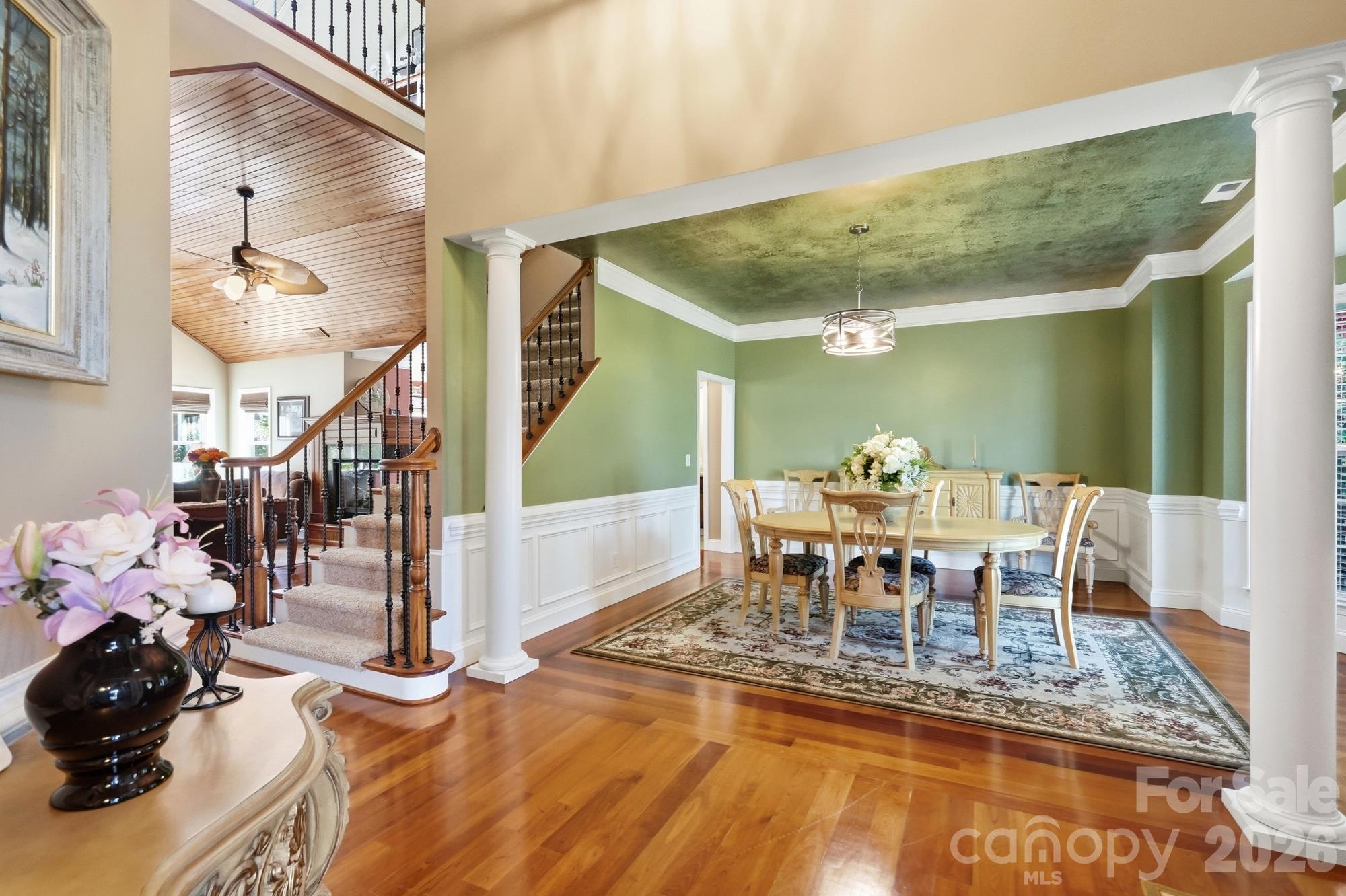 Walking out of the office into the foyer, you are graced by the elegant dining room and can see into the open floor plan and side stairs with custom scroll railing and wrought iron spindles. - 120 Harris Farm Road, Mooresville