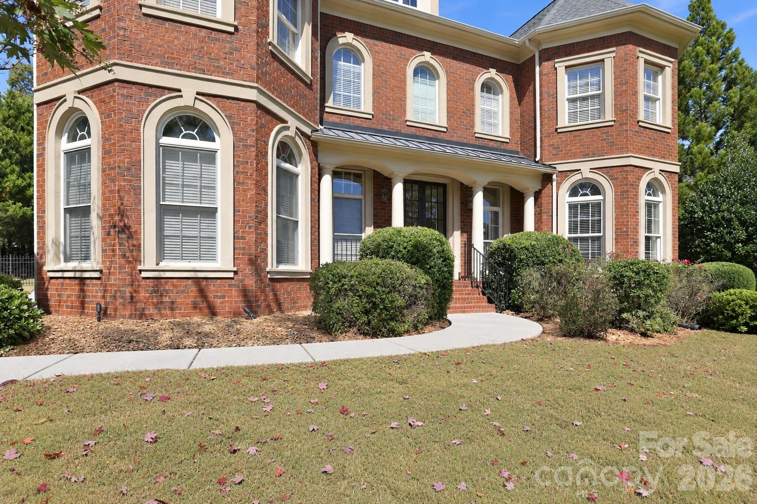 A curved walkway leads to the covered front entry where stately columns, brick steps and double doors create an impressive welcome. - 2309 Highland Forest Drive, Waxhaw