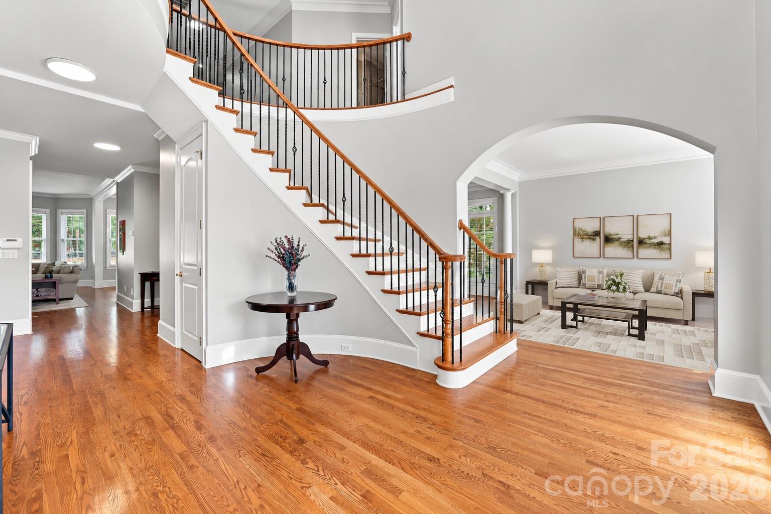 The grand two-story foyer welcomes you inside, where the sweeping staircase immediately catches your eye and the formal living room is framed by a wide arched opening. - 2309 Highland Forest Drive, Waxhaw