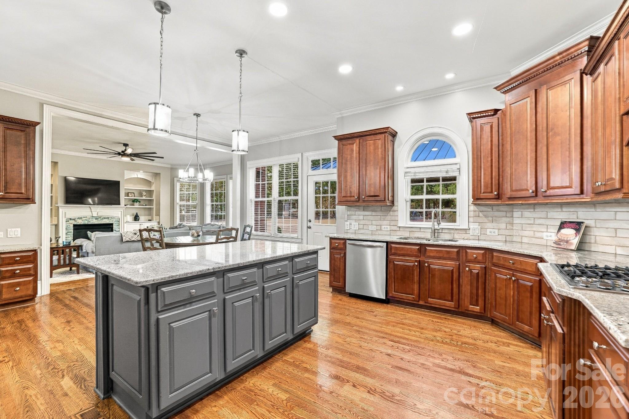 Warm maple cabinetry, granite countertops, a tiled backsplash, hardwood floors and distinctive lighting give this kitchen a rich, custom look. Stainless steel appliances include a gas cooktop, double wall ovens and dishwasher while two pantries provide plenty of storage. Wide-open sight lines into the great room mean the cook can be part of the conversation whether it’s a casual night at home or a houseful of guests. - 2309 Highland Forest Drive, Waxhaw