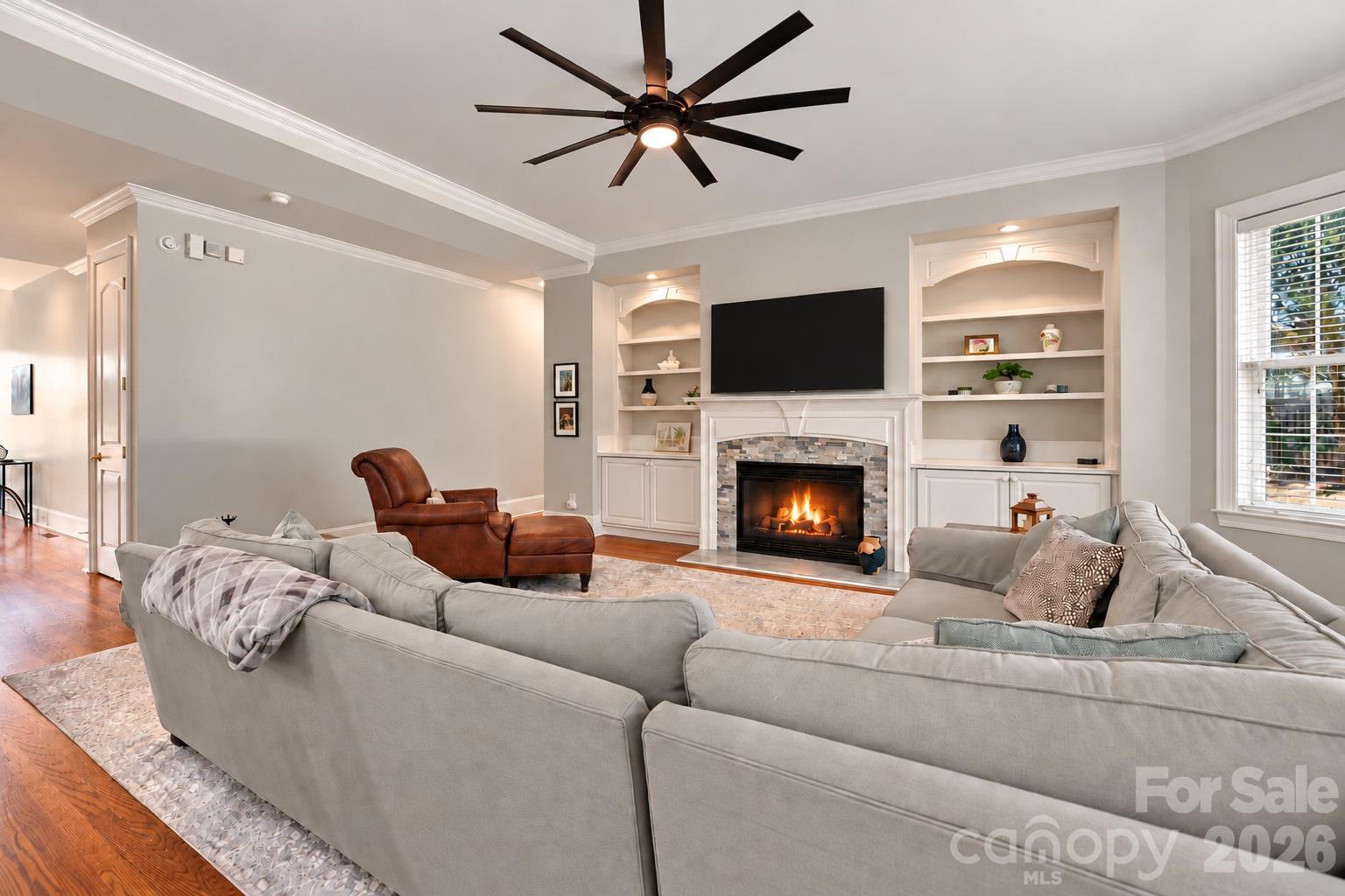 The gas fireplace creates a warm focal point, framed by custom built-ins with display shelving, cabinetry and accent lighting — a great combination of architectural detail and useful storage. - 2309 Highland Forest Drive, Waxhaw