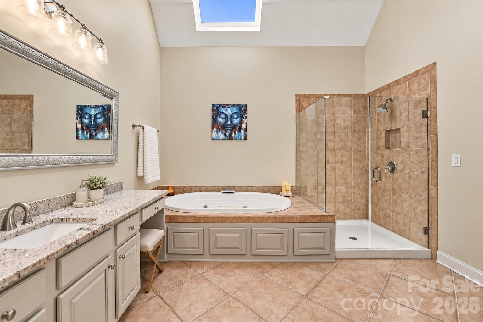 A primary bath made for unwinding, with a deep soaking tub beneath the skylight, a large walk-in shower with frameless glass enclosure, extensive tilework and granite-topped vanities. Two closets outside the entrance to the bathroom add the kind of storage you can never have too much of. - 2309 Highland Forest Drive, Waxhaw