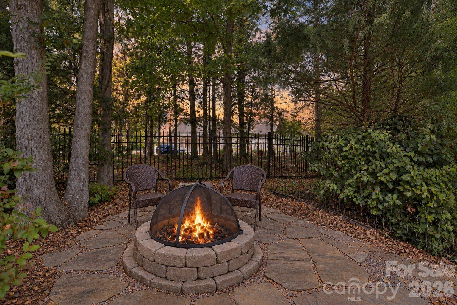 Tucked beneath the trees, the backyard fire pit creates a cozy spot for cool evenings outside. Pull up a chair, light the fire and settle in for conversation, a glass of wine or simply a little time under the stars. - 2309 Highland Forest Drive, Waxhaw