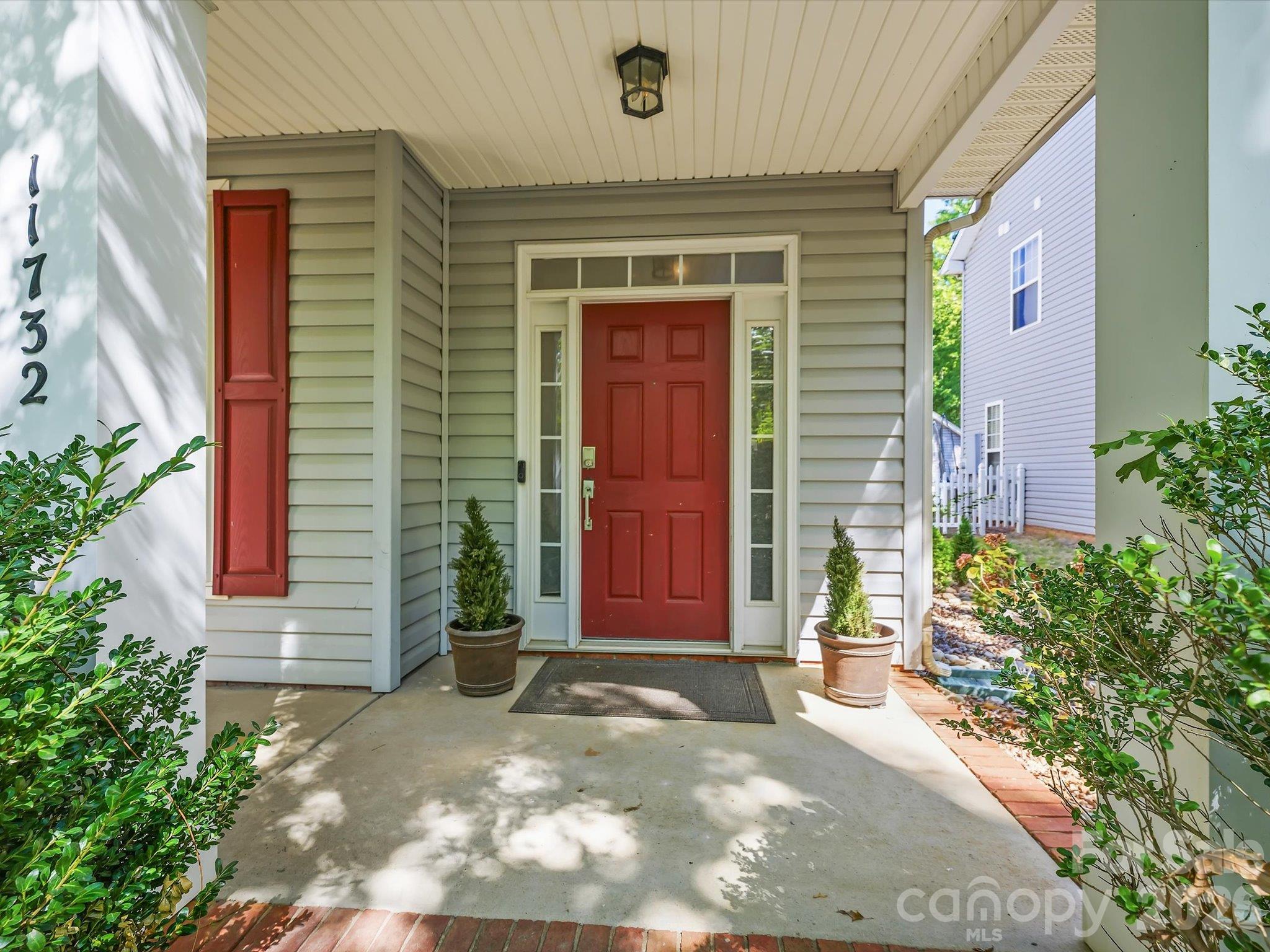 A charming two-story home with a welcoming covered front porch, mature landscaping, and classic architectural details creates inviting curb appeal. - 11732 Windy Mist Way, Huntersville