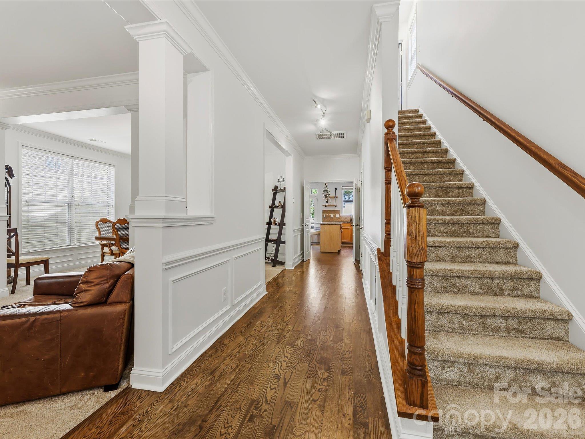 A welcoming foyer features warm hardwood floors, elegant millwork, and a classic staircase that creates an inviting transition into the home’s main living spaces. - 11732 Windy Mist Way, Huntersville