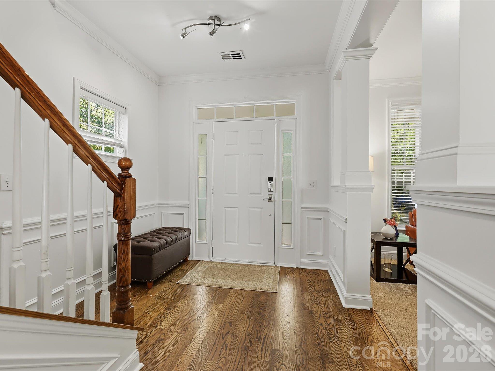 A welcoming foyer features warm hardwood floors, elegant millwork, and a classic staircase that creates an inviting transition into the home’s main living spaces. - 11732 Windy Mist Way, Huntersville