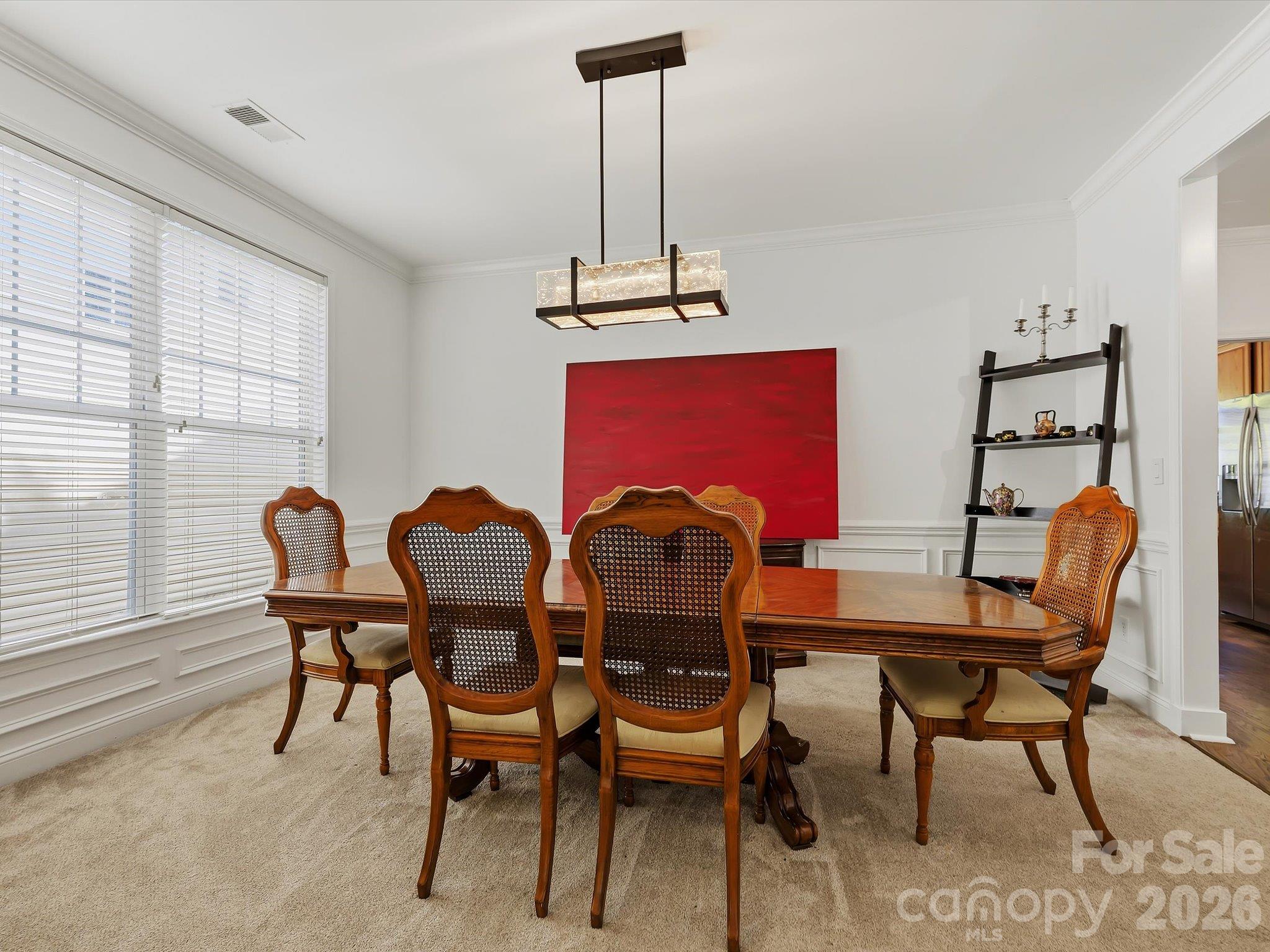 A spacious formal dining room features elegant crown molding, architectural columns, and a contemporary statement light fixture, creating an inviting setting for gatherings and entertaining. - 11732 Windy Mist Way, Huntersville
