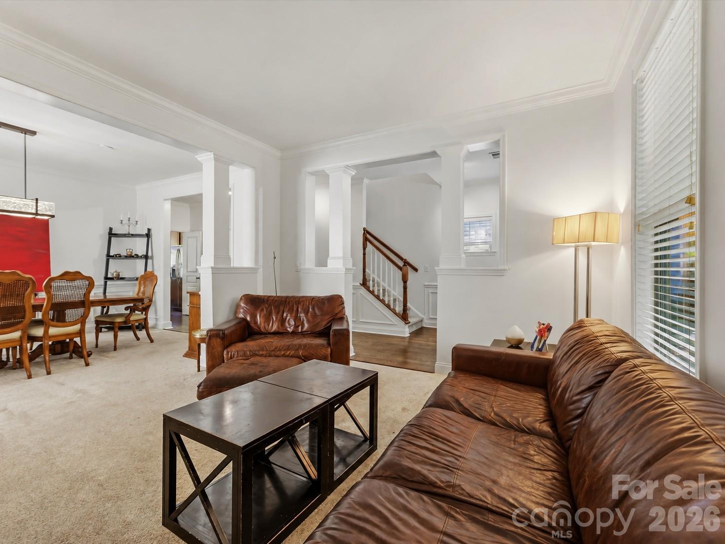 A spacious living room features abundant natural light, elegant crown molding, and an open connection to the dining area for comfortable everyday living and entertaining. - 11732 Windy Mist Way, Huntersville