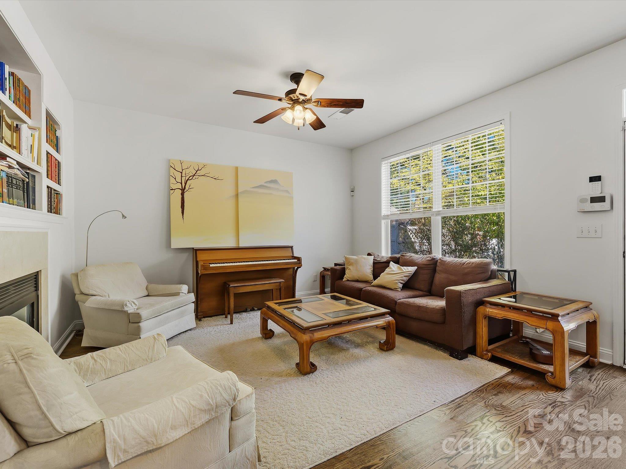 A bright great room features a cozy fireplace (in "as is" condition) with built-in shelving, hardwood floors, and abundant natural light for comfortable everyday living. - 11732 Windy Mist Way, Huntersville