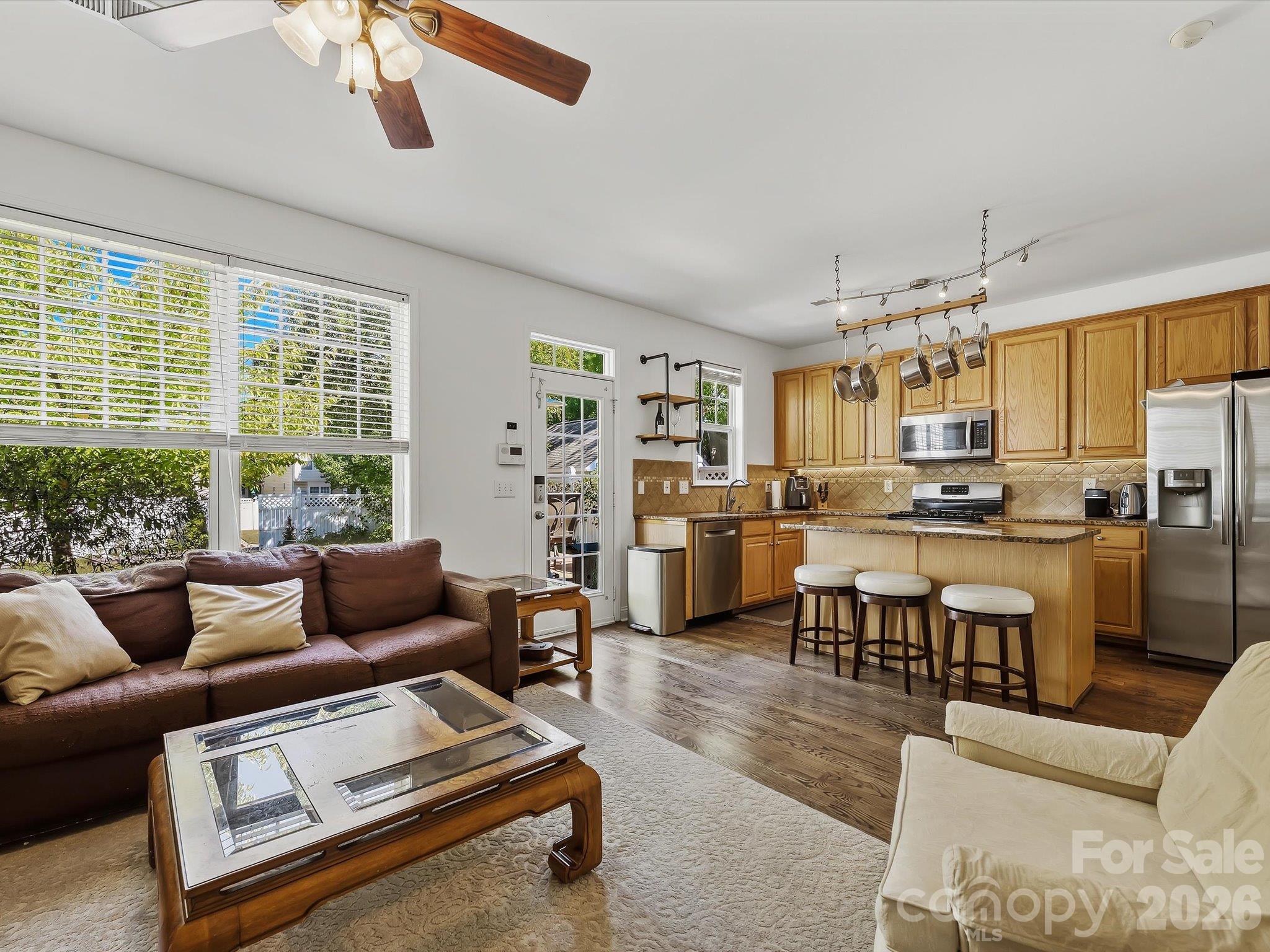 The open-concept great room flows seamlessly into the kitchen, featuring hardwood floors, a cozy fireplace (in "as is" condition) with built-in shelving, abundant natural light, and a breakfast bar for casual seating. - 11732 Windy Mist Way, Huntersville