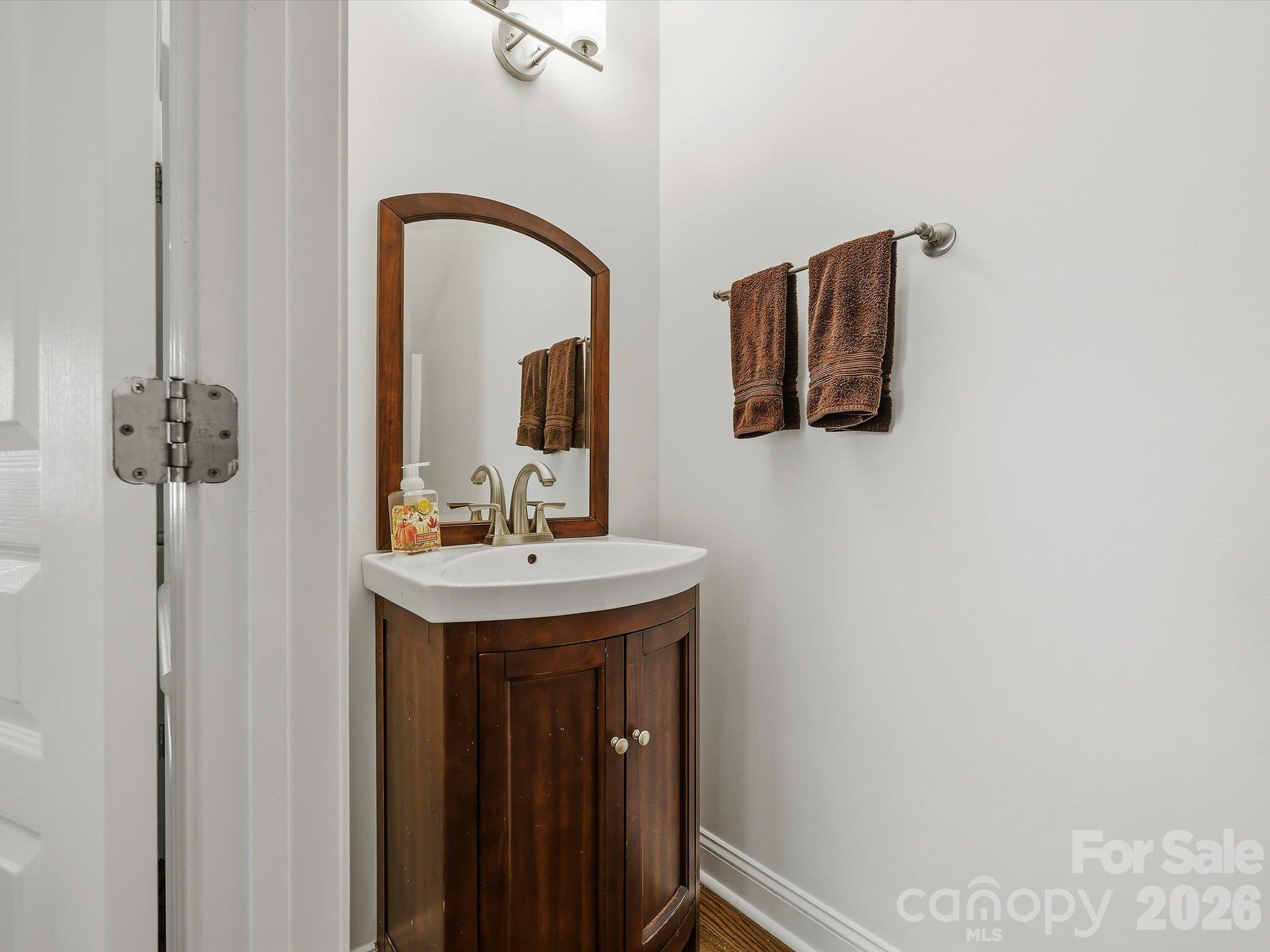 A conveniently located powder room features a warm wood vanity, stylish framed mirror, and clean neutral finishes. - 11732 Windy Mist Way, Huntersville