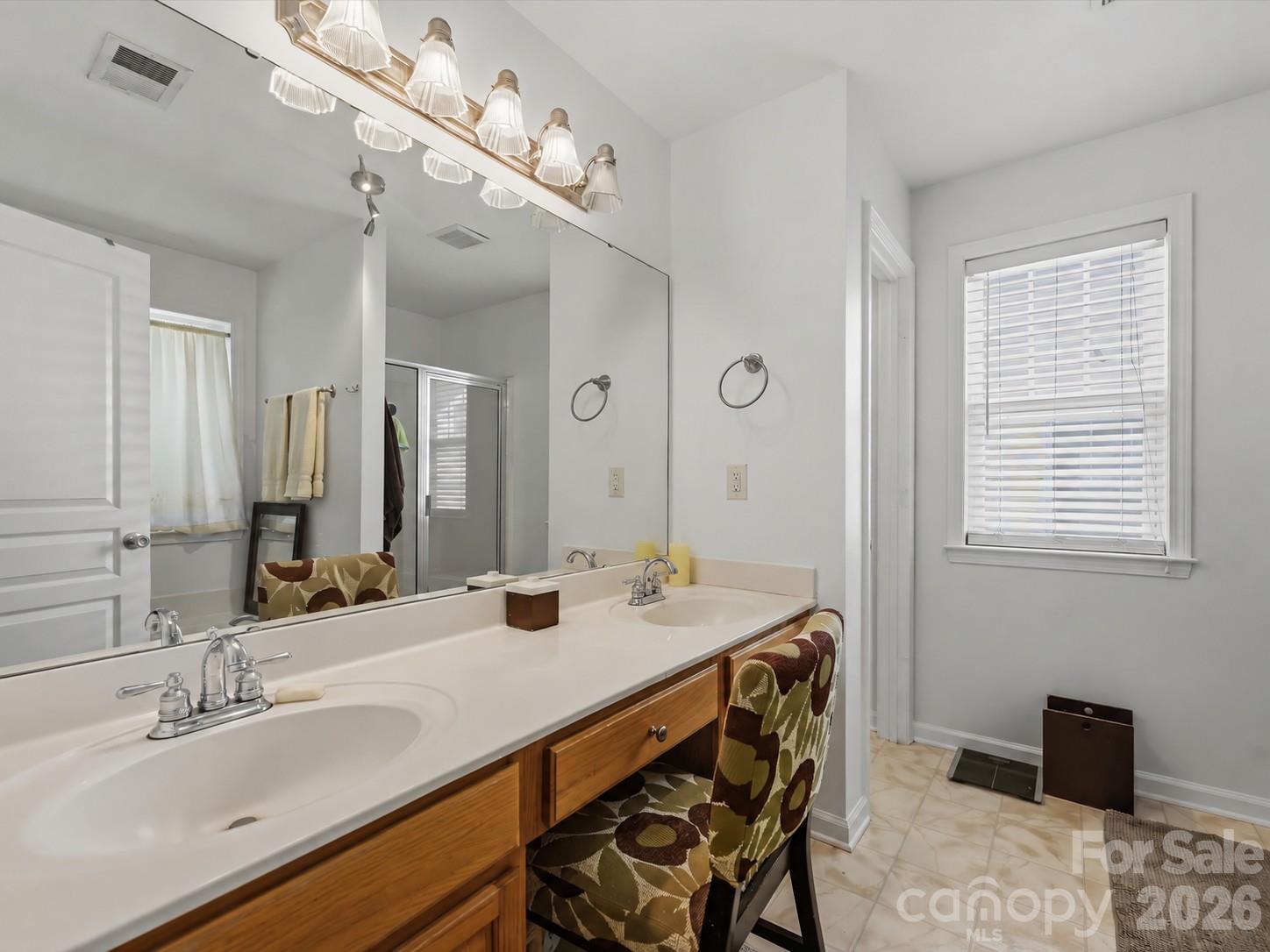 The Primary Bath features a dual-sink vanity, separate glass-enclosed shower, soaking tub, and abundant natural light. - 11732 Windy Mist Way, Huntersville