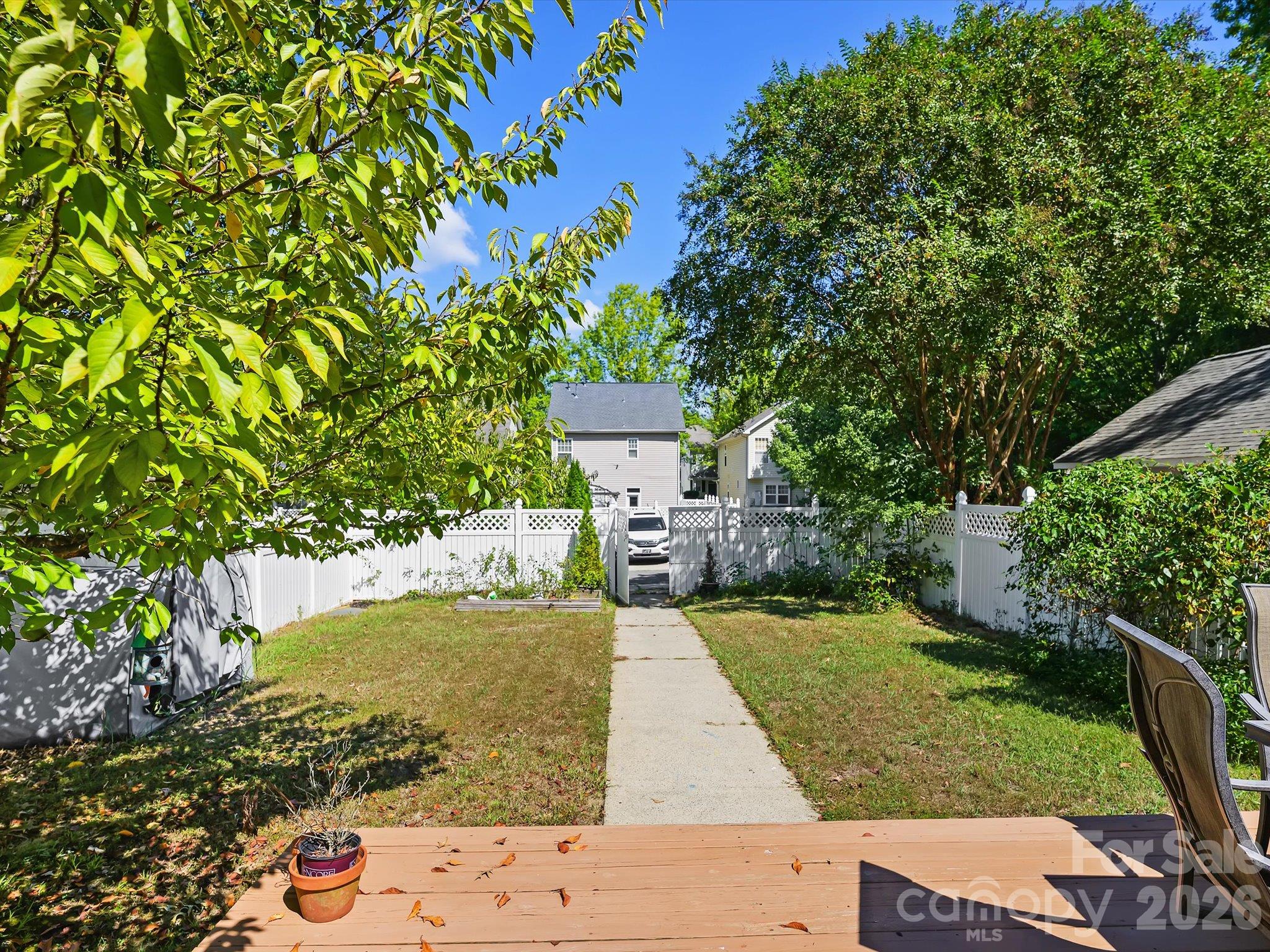 The back deck overlooks a fenced backyard with mature trees and green space, providing a private setting for outdoor relaxation and entertaining. - 11732 Windy Mist Way, Huntersville