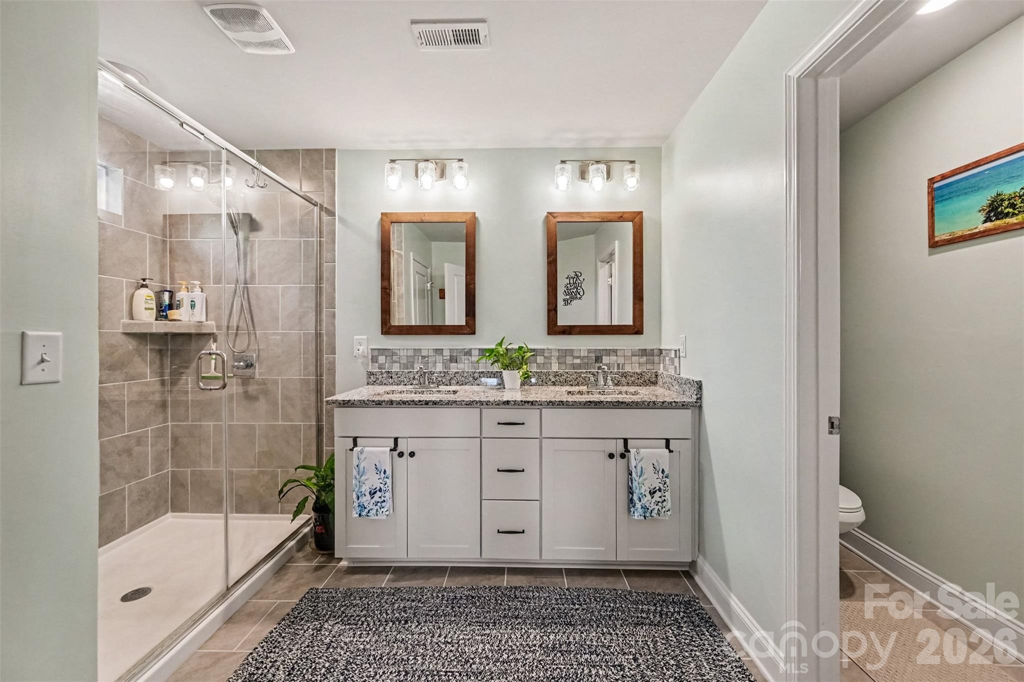 The primary bath has dual vanities and a tiled walk-in shower. - 2703 Wedgewood Court, Denver