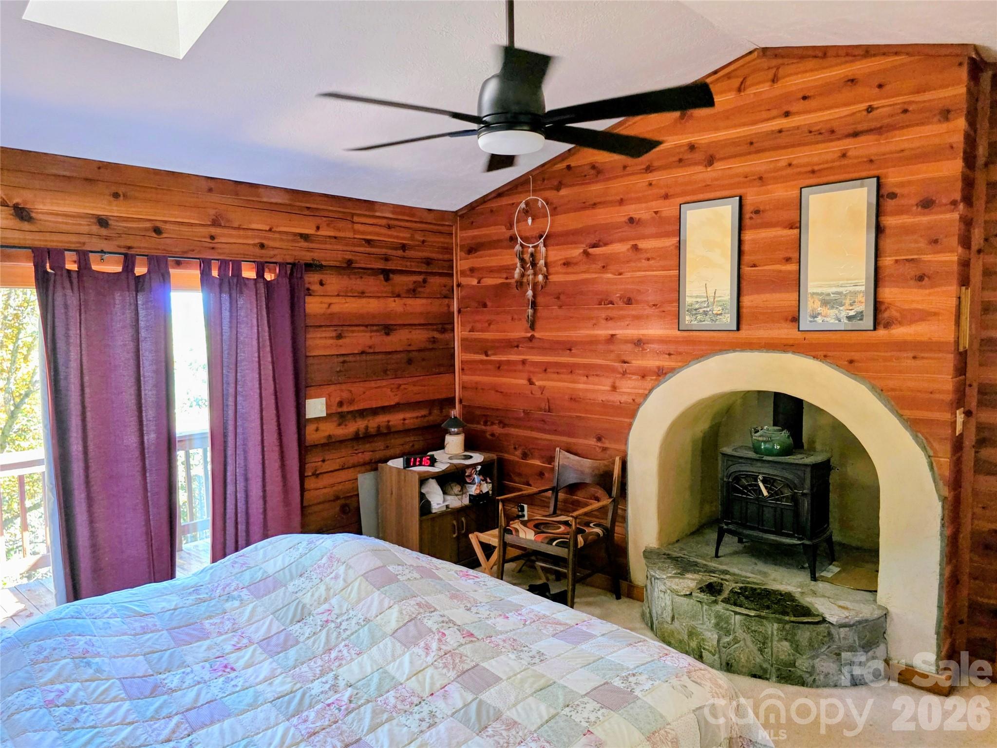 Interior of log walls in the primary bedroom with view of wood stove - 105 Poplar Ridge Lane, Burnsville