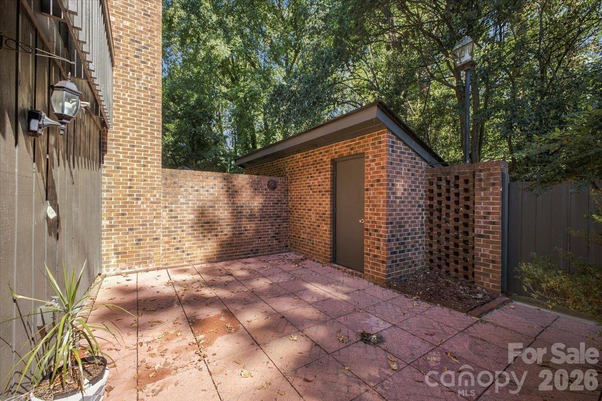 Back patio with brick pavers and enclosed storage with shelves - 5805 Sharon Road, Charlotte