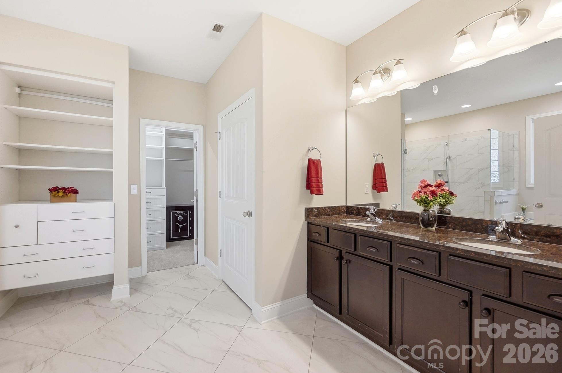 Remodeled primary bath boasting dual vanities, large shower, soaking tub, towel warming rack, and custom walk-in closet - 9106 Longvale Lane, Charlotte