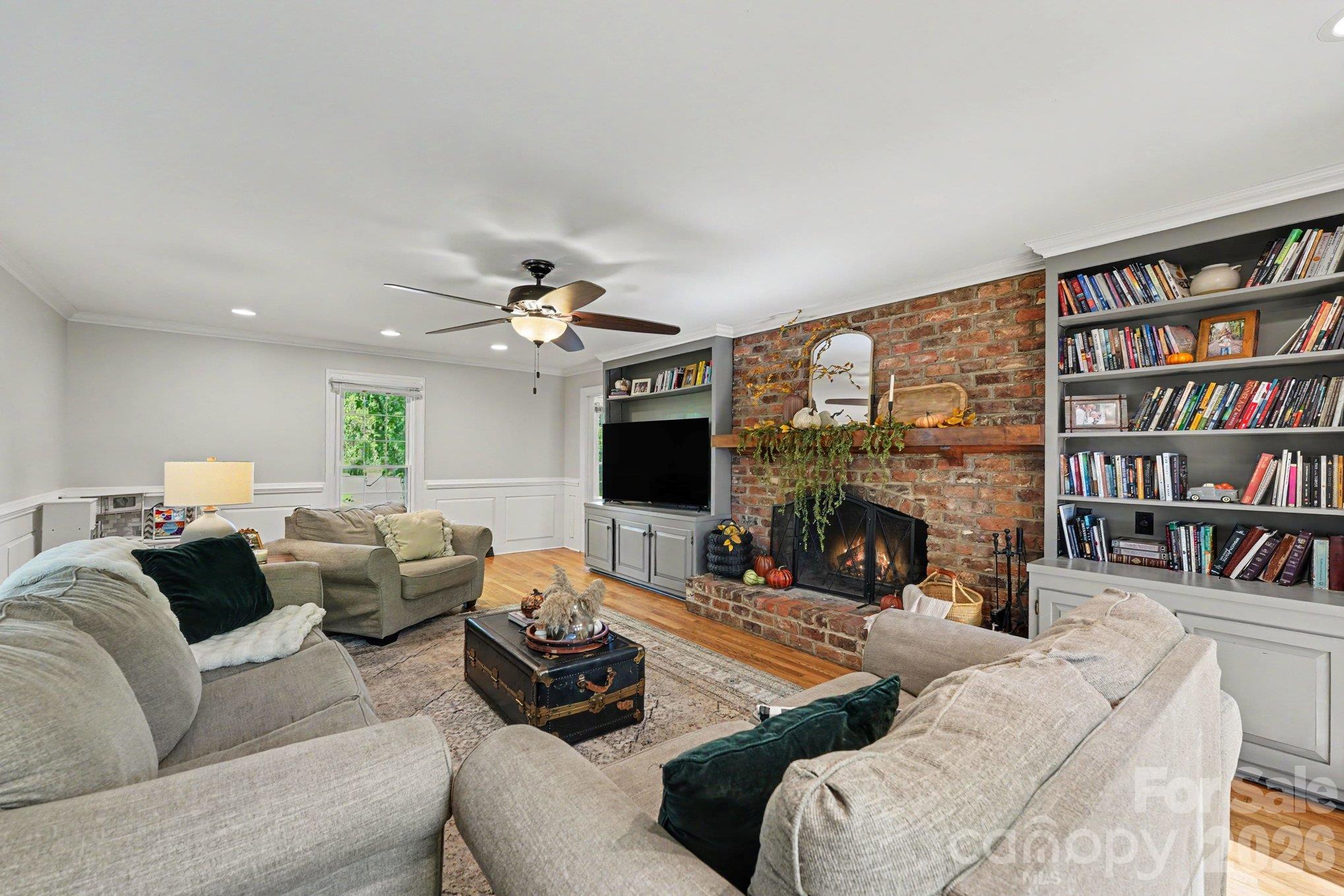 Stunning brick fireplace anchors this inviting living room, complemented by built-in bookcases and cabinetry, and classic wall moldings. Natural light adds to the welcoming atmosphere, creating a beautiful space to gather or unwind. - 607 Anderson Avenue, Salisbury