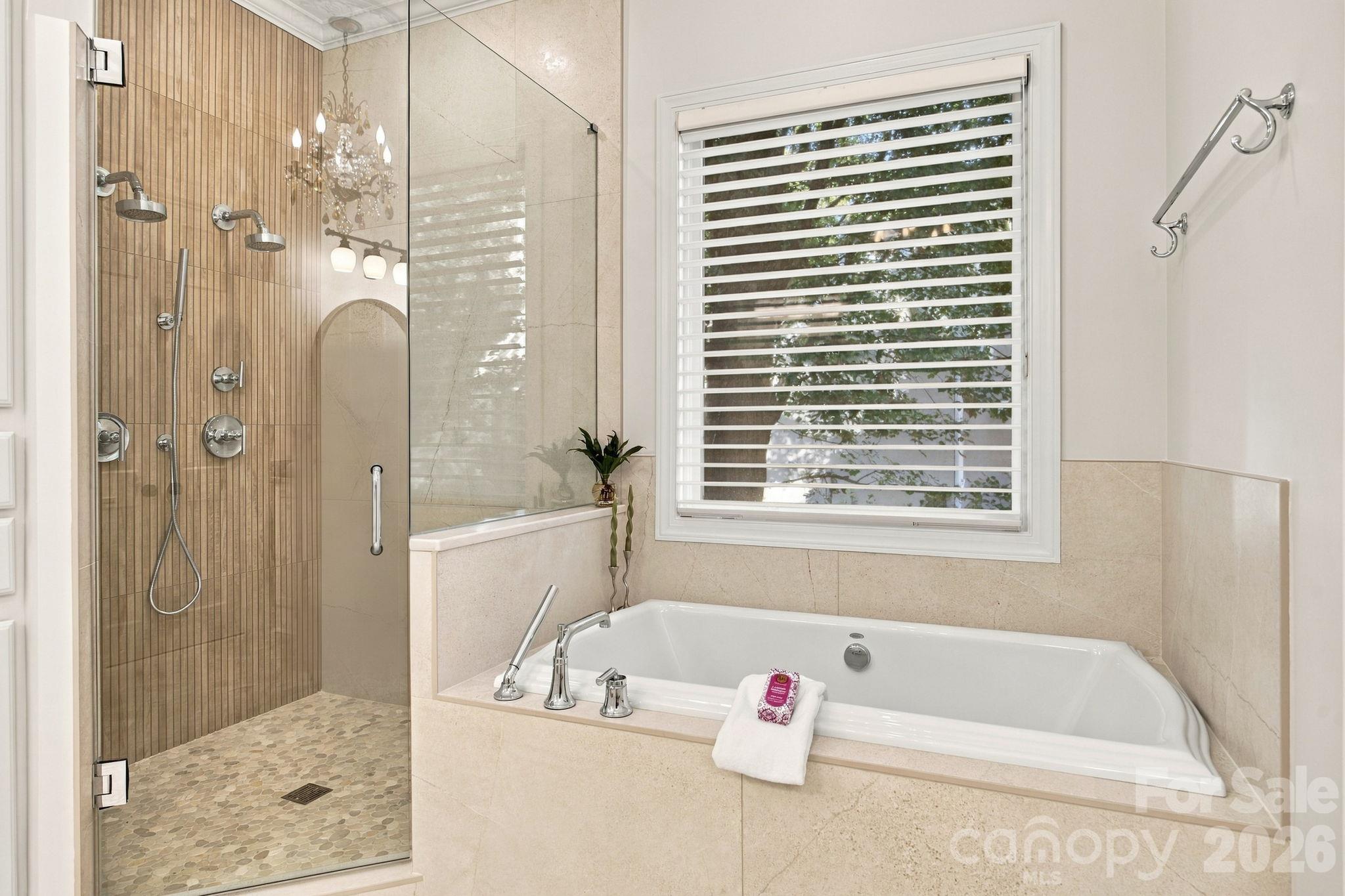 A serene primary bathroom featuring a relaxing soaking tub and separate shower. - 18416 Peninsula Club Drive, Cornelius