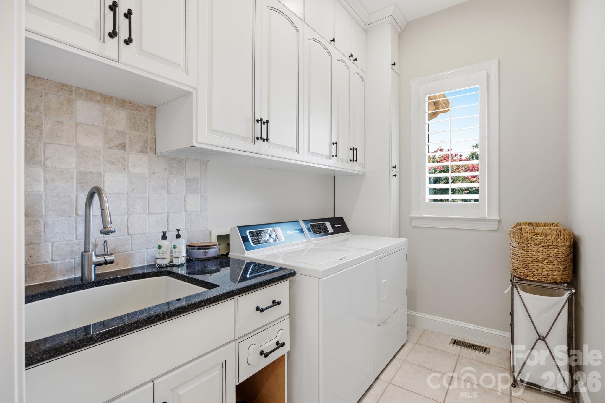 A clean, functional laundry room equipped with upper storage cabinets. - 18416 Peninsula Club Drive, Cornelius