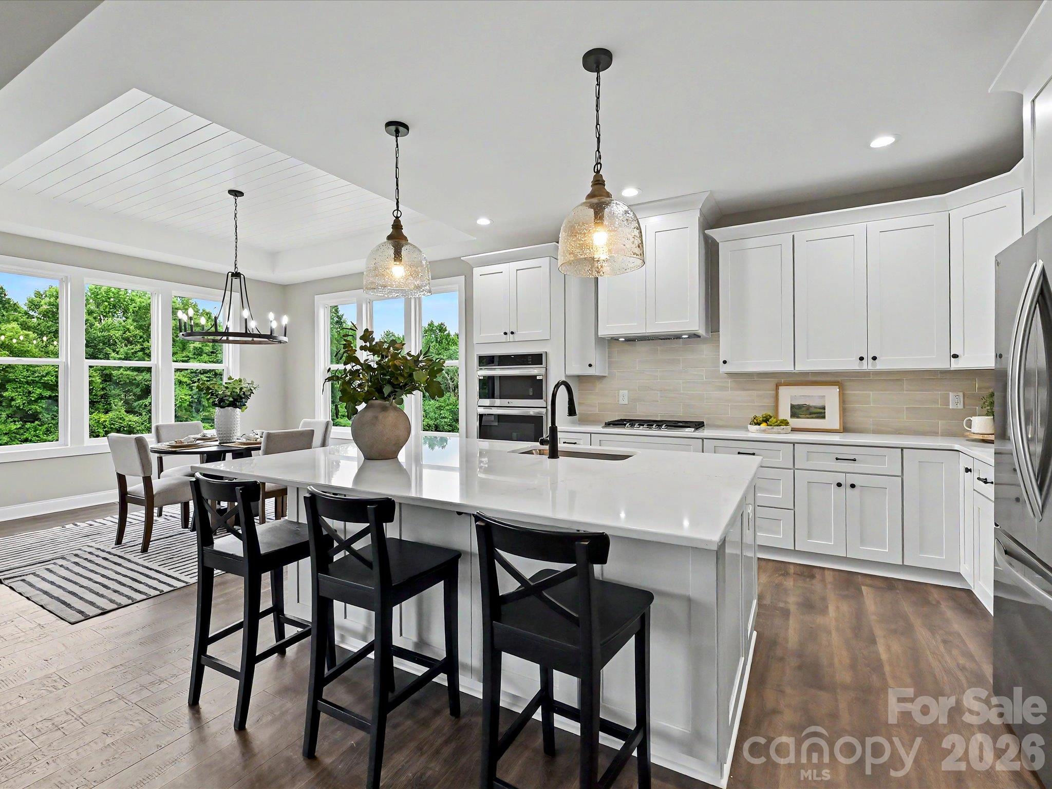 Designer kitchen features a massive quartz island, custom cabinetry, stainless steel appliances & an open layout perfect for everyday living & entertaining. - 159 Lone Pine Road, Statesville