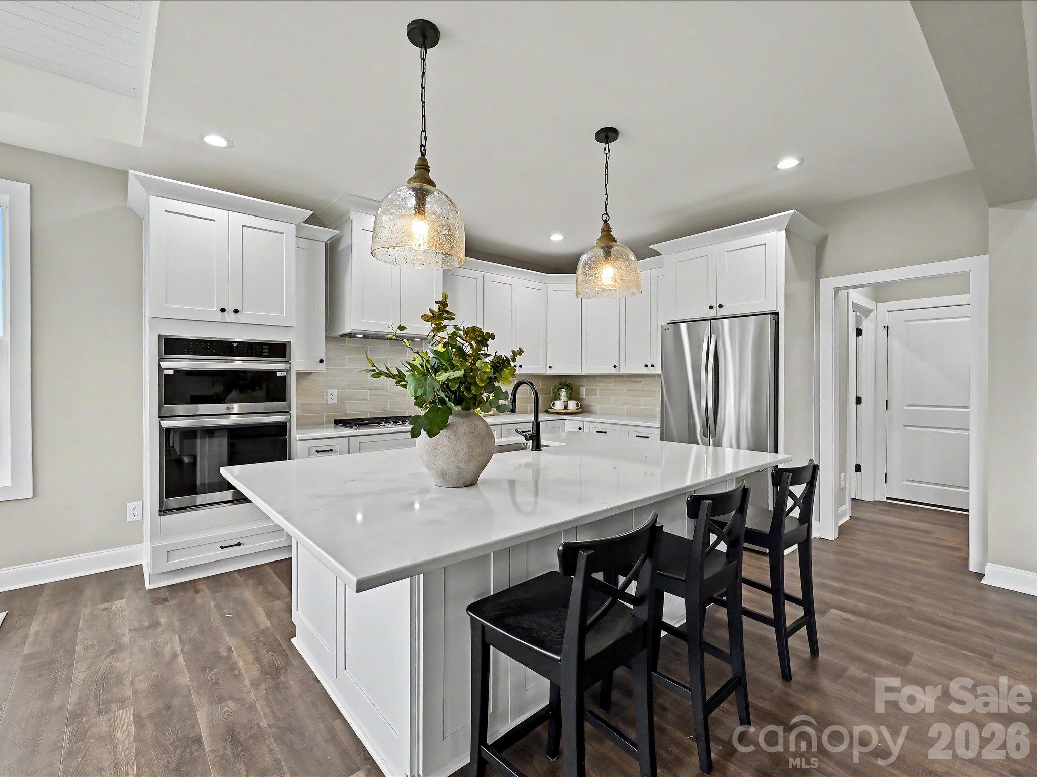 Designer kitchen features a massive quartz island, custom cabinetry, stainless steel appliances & an open layout perfect for everyday living & entertaining. - 159 Lone Pine Road, Statesville