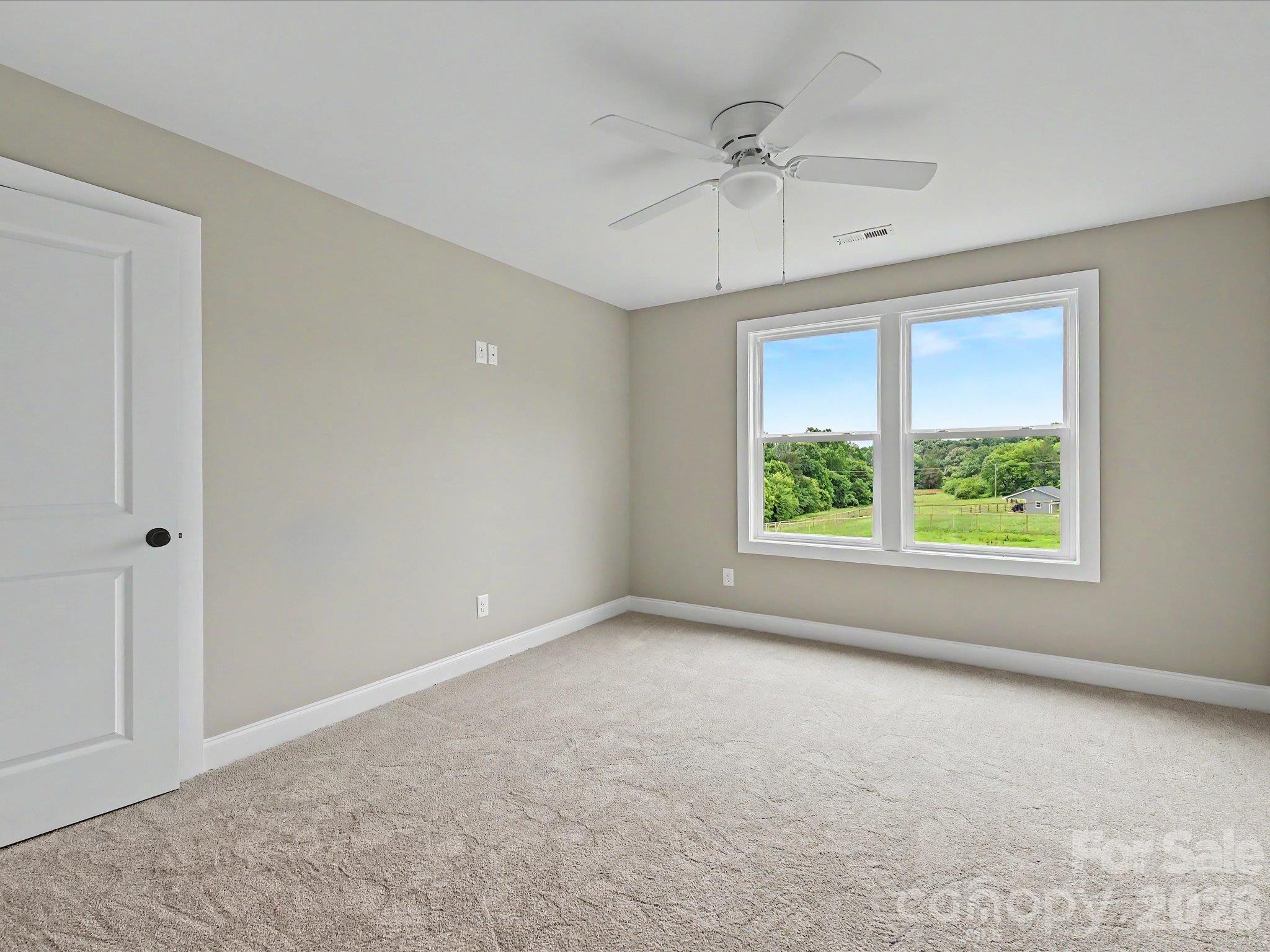 Bright secondary bedroom on upper level features soft carpeting, ceiling fan & large windows showcasing scenic countryside views. - 159 Lone Pine Road, Statesville