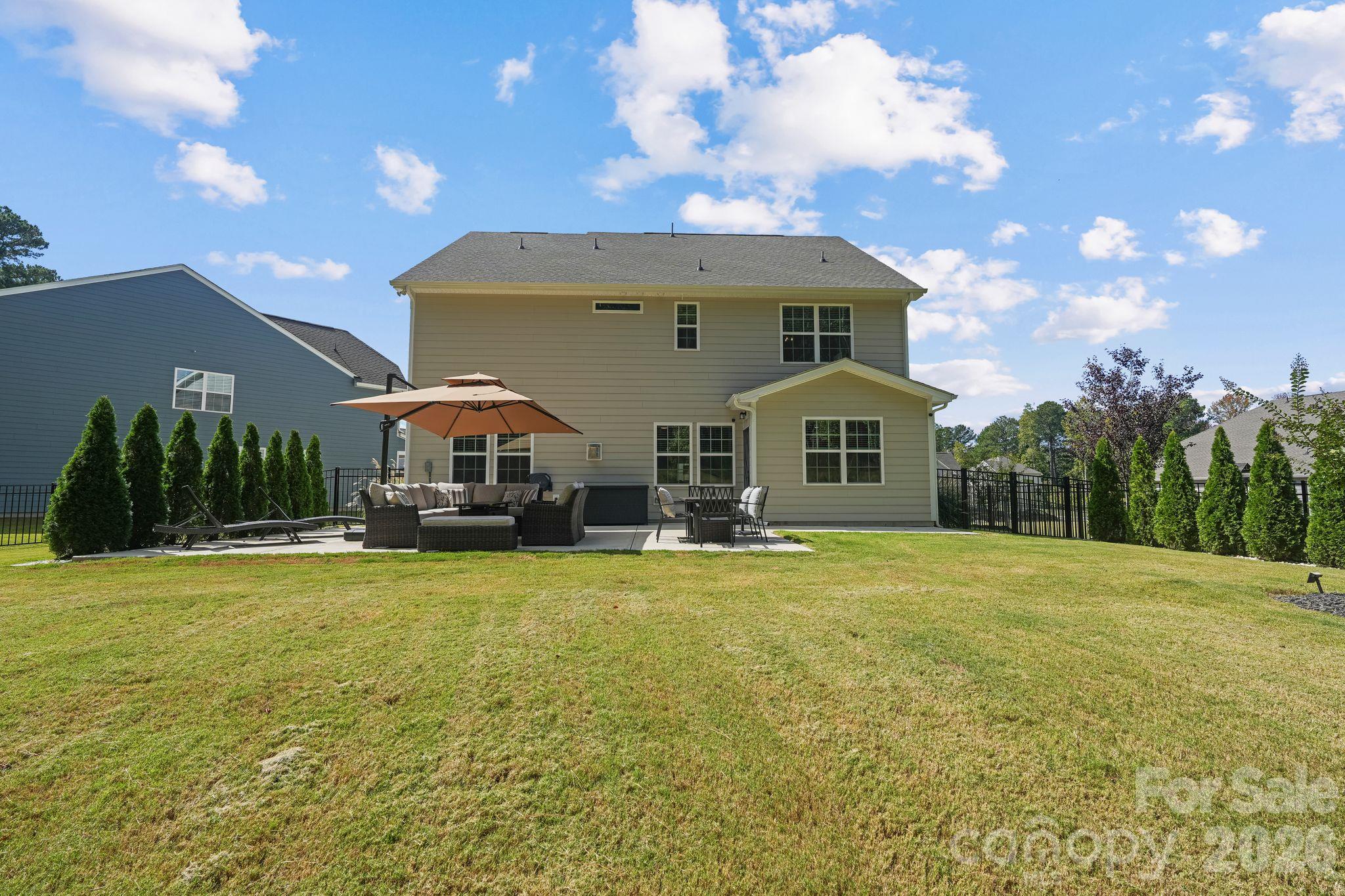 Beautifully landscaped, fully fenced backyard featuring an oversized concrete patio and thoughtfully planted trees for added privacy. - 107 Hollywood Court, Troutman